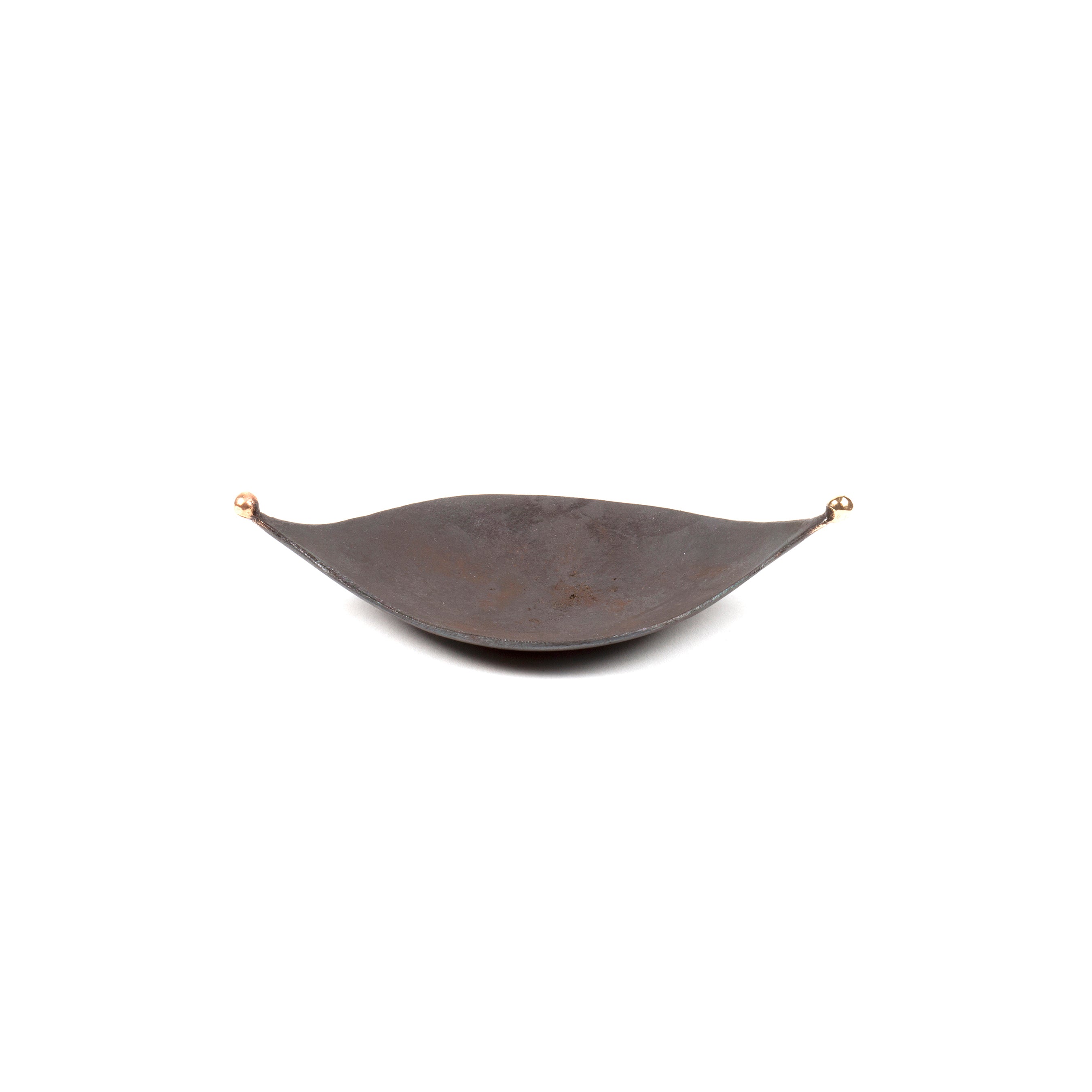 The Knopferl Tray #3431 by Werkstätte Carl Auböck is a crescent-shaped, matte black design with two golden knobs, reflecting minimalist elegance. Its smooth surface and curved form capture modernity reminiscent of mid-century exhibitions like the Triennale di Milano 1954.
