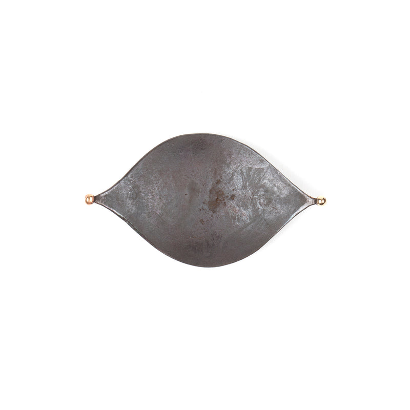 The Knopferl Tray #3431, an elongated, eye-shaped metallic piece with small spherical ends, designed by Werkstätte Carl Auböck, is seen against a plain white background.