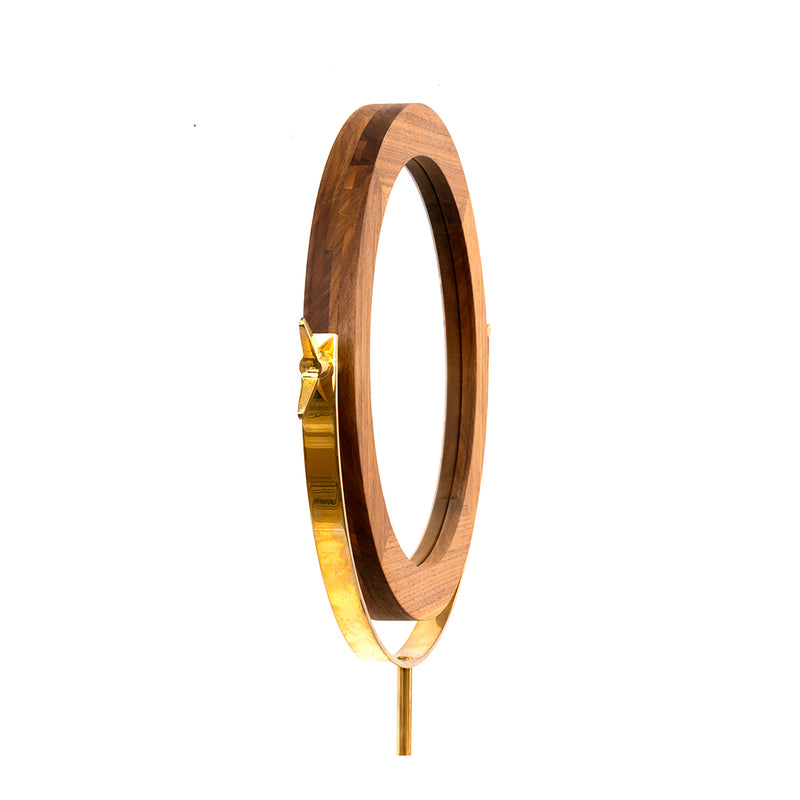 Mirror #4959 by Werkstätte Carl Auböck features a wooden circular frame on a gold stand with side view, evoking the charm of a Viennese townhouse. Set against a white background, the design includes a star-like decorative element reminiscent of Auböcks timeless style.