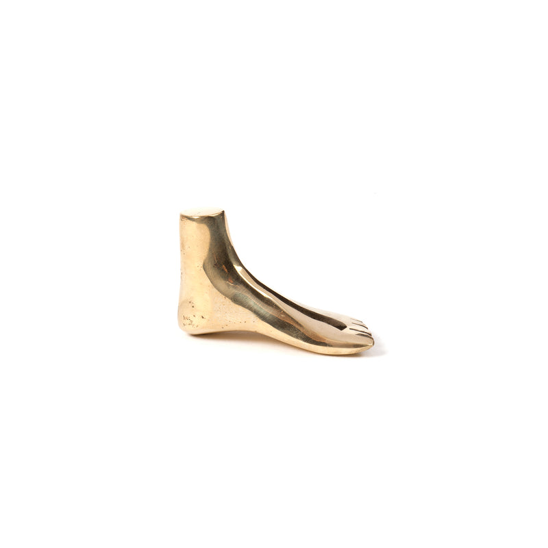 A side bronze sculpture, Paperweight Foot #4273 by Werkstätte Carl Auböck, sits on a white background. It features a stylized, simplified design with a smooth surface reminiscent of polished brass.
