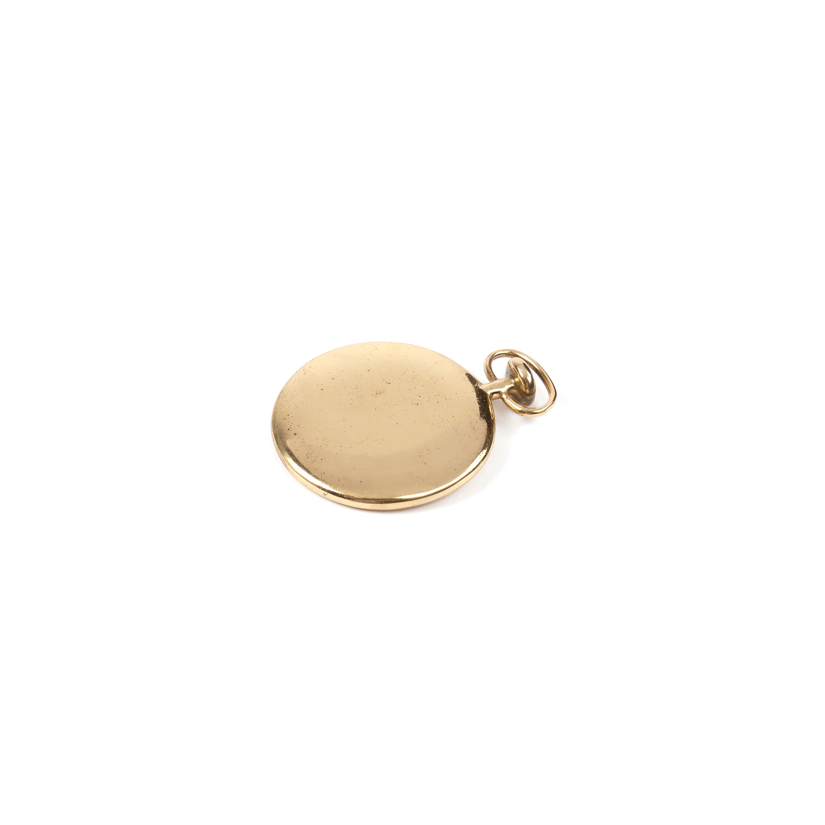 The Werkstätte Carl Auböck Paperweight Watch #4626 is a round, flat, shiny gold pendant exuding elegance with its small loop for necklace attachment. It rests on a white background, with a smooth, reflective surface showcasing craftsmanship reminiscent of Wiener Bronzen artistry.