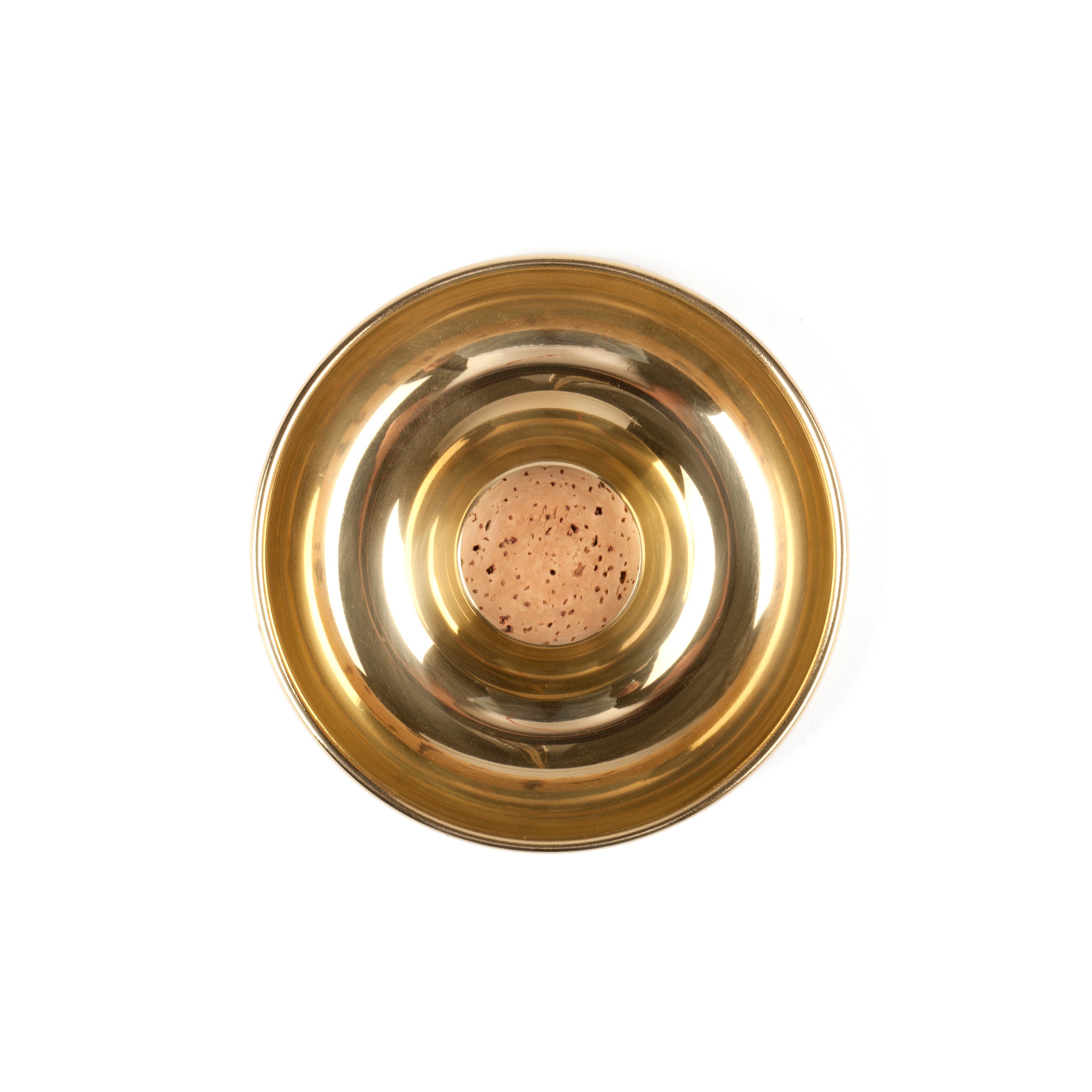 The Pipe Ashtray #7201 by Werkstätte Carl Auböck is a round, gold-hued metallic plate with a central cork insert featuring speckled Viennese patterns. Its circular shape and shiny elegance are visible from above against a plain white background.