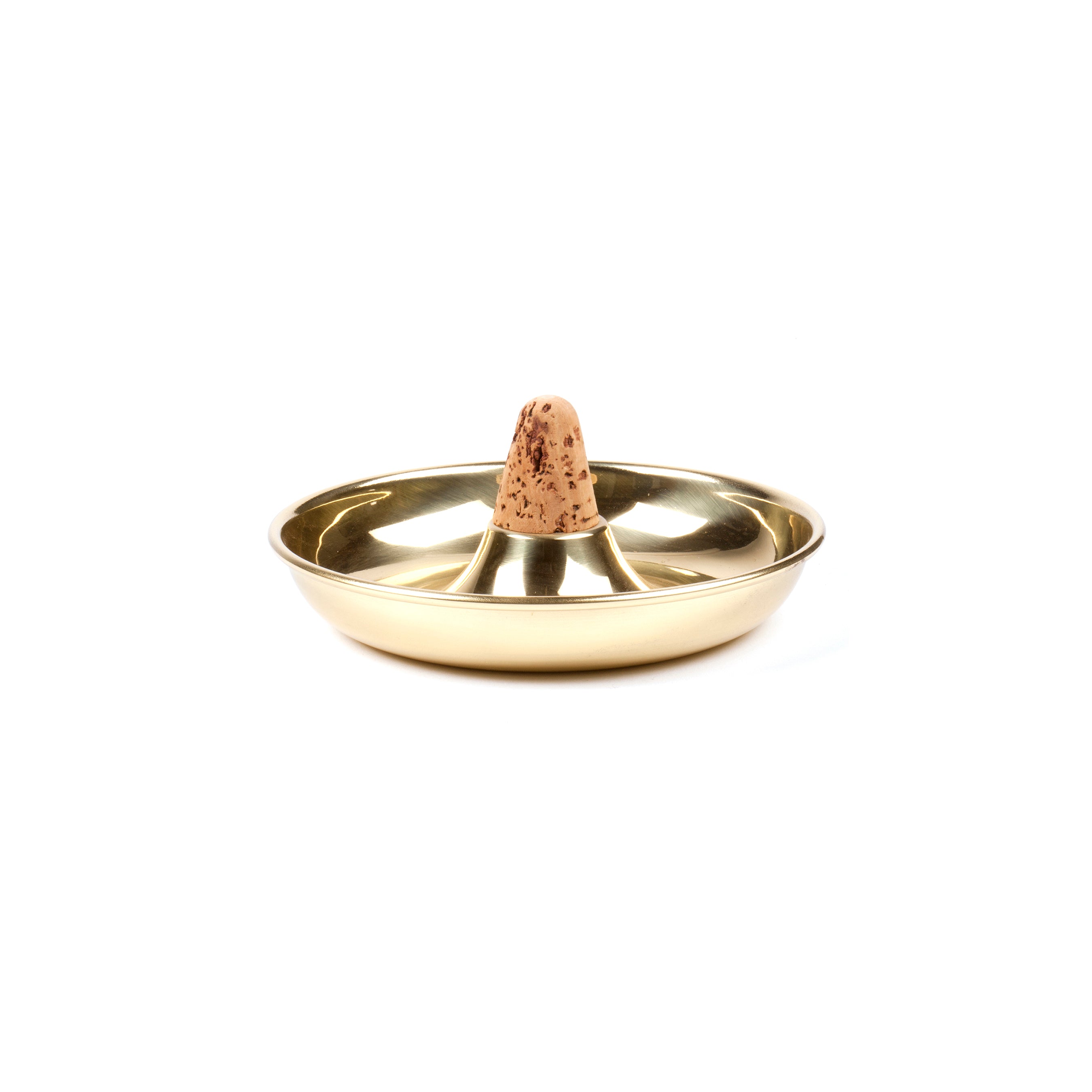 This gold-colored metal incense holder by Werkstätte Carl Auböck, called Pipe Ashtray #7202, features a central cone-shaped incense stick. Its shiny, round surface elegantly reflects light, and the brown incense cone displays a speckled pattern.