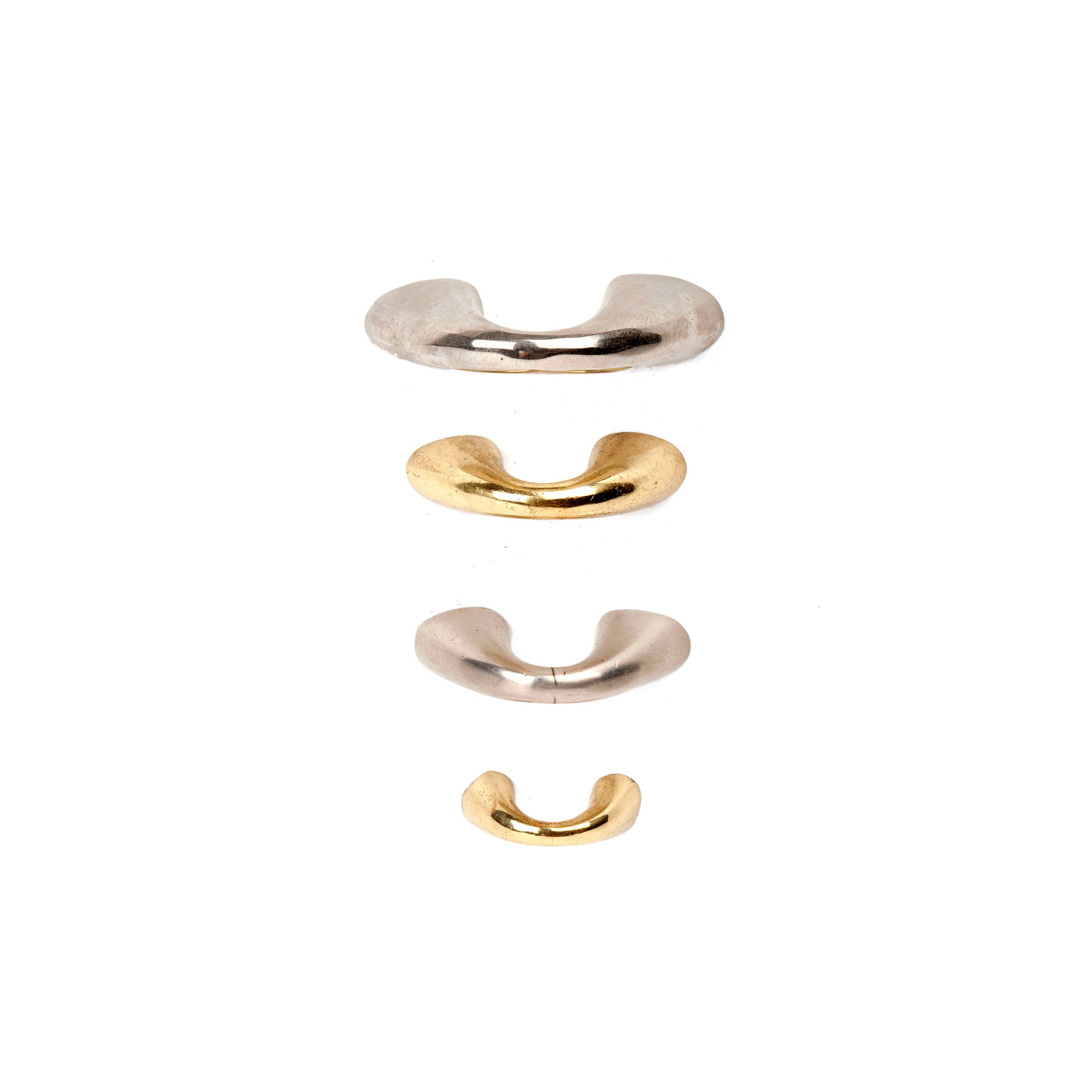 Puller #9030 #9031 by Werkstätte Carl Auböck features a minimalist design with four curved metallic rings on a white background. Silver top and third rings are paired with gold second and fourth, creating a brass-inspired, visually balanced composition.