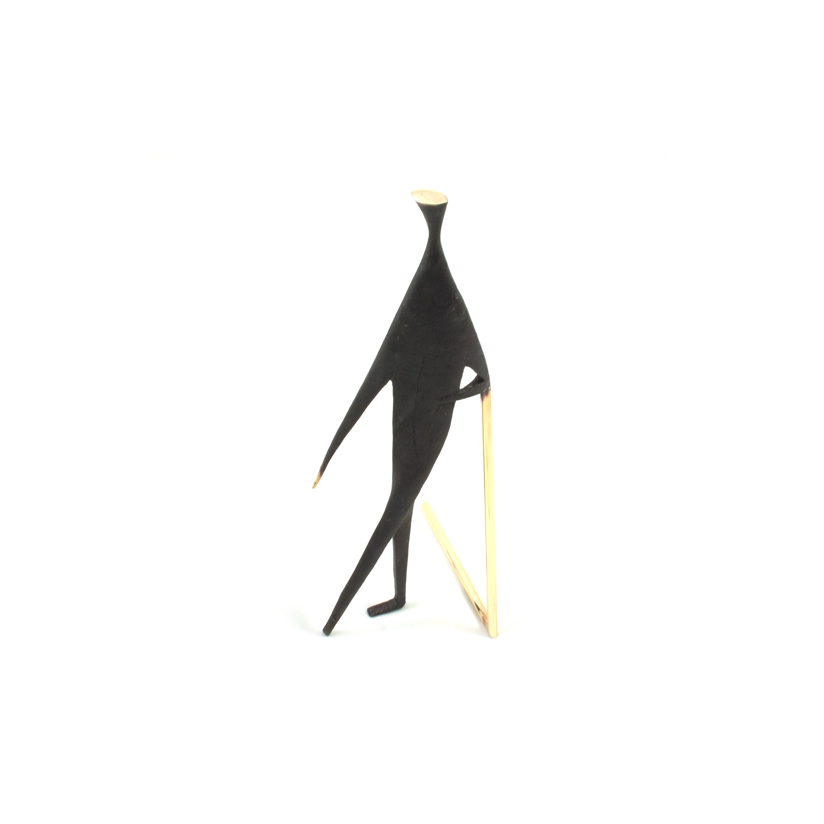 Sculpture #4060 by Werkstätte Carl Auböck features a minimalist humanoid figure in black, walking with a cane. It boasts abstract elongated limbs and a small head, all set against a plain white background.