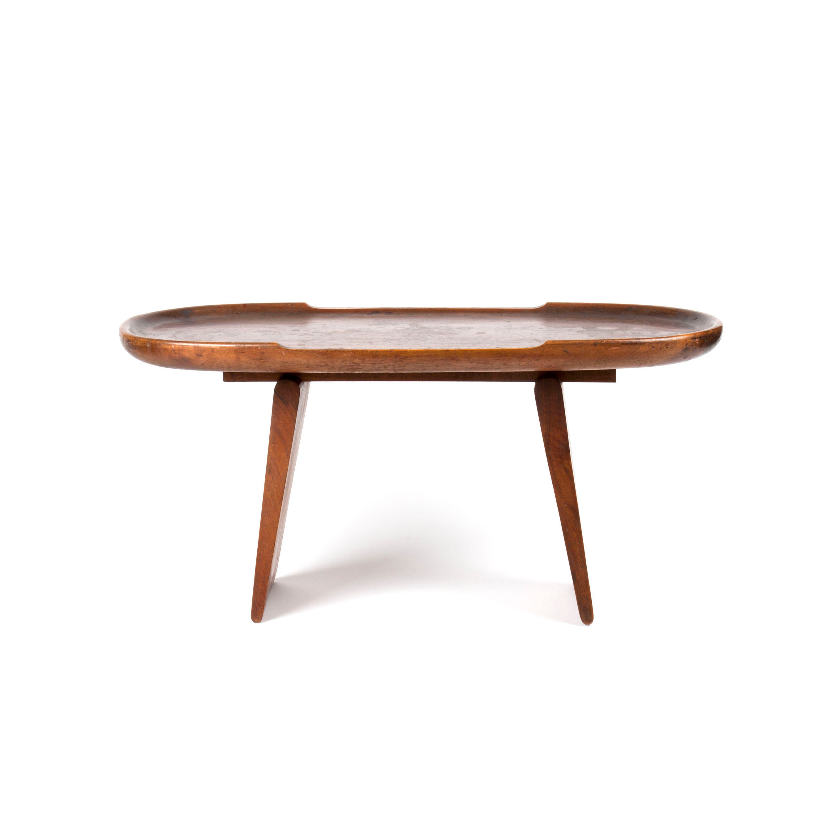 The Table #3511 by Werkstätte Carl Auböck is a wooden mid-century modern coffee table with a rounded rectangular top and three angled legs, seen front-on against a white background.