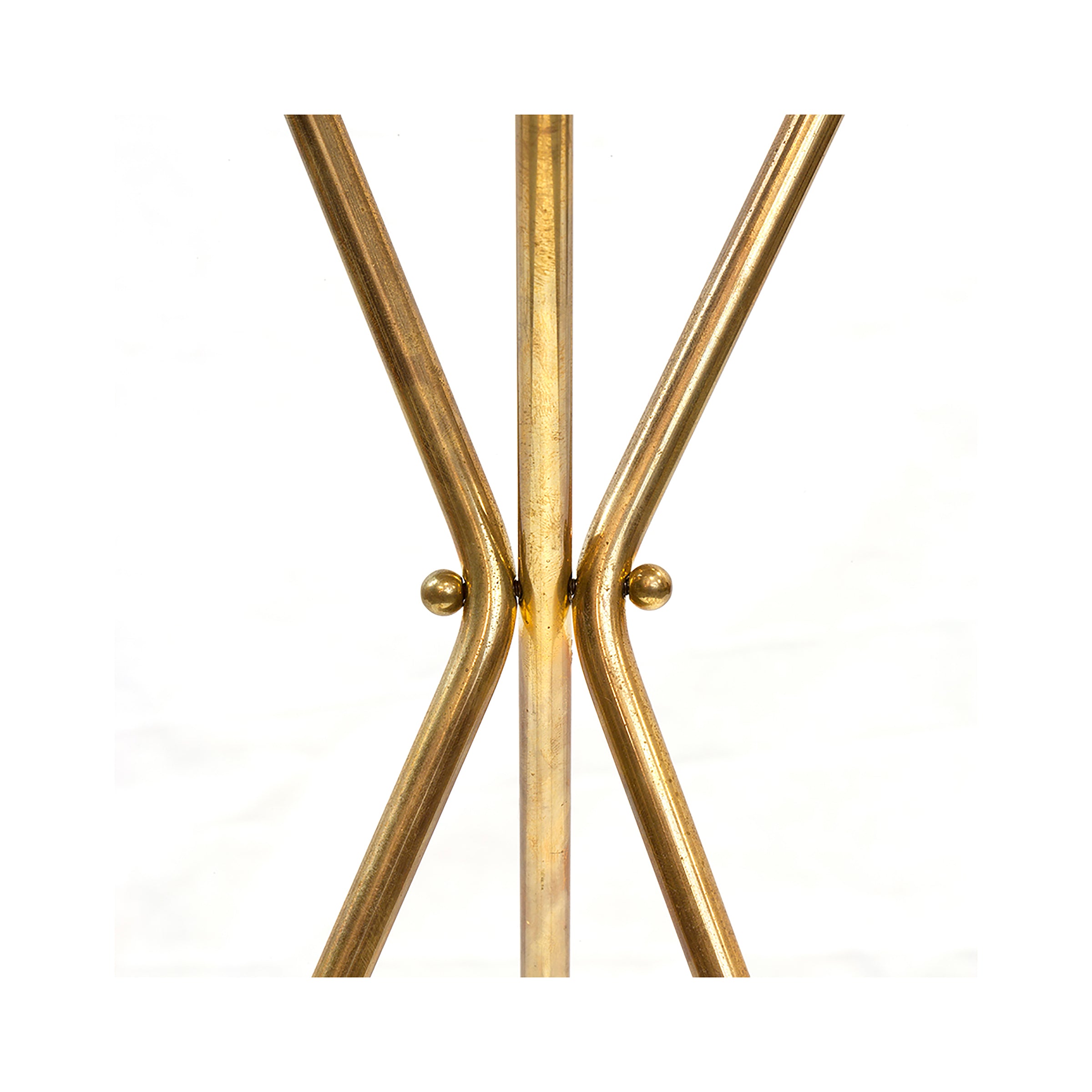 A close-up of Sidetable #3642 by Werkstätte Carl Auböck features two intersecting gold-colored rods in an X shape, joined by small circular knobs. The plain white background accentuates its elegance, reminiscent of pieces displayed at Triennale di Milano.
