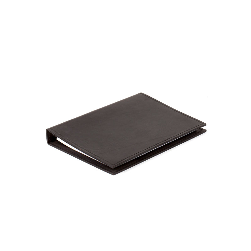 A sleek, closed black leather Telephone Register #5116/1 by Werkstätte Carl Auböck is set against a white backdrop. Its minimalist design echoes the elegance of a Viennese townhouse, with no visible branding to detract from its simple beauty.