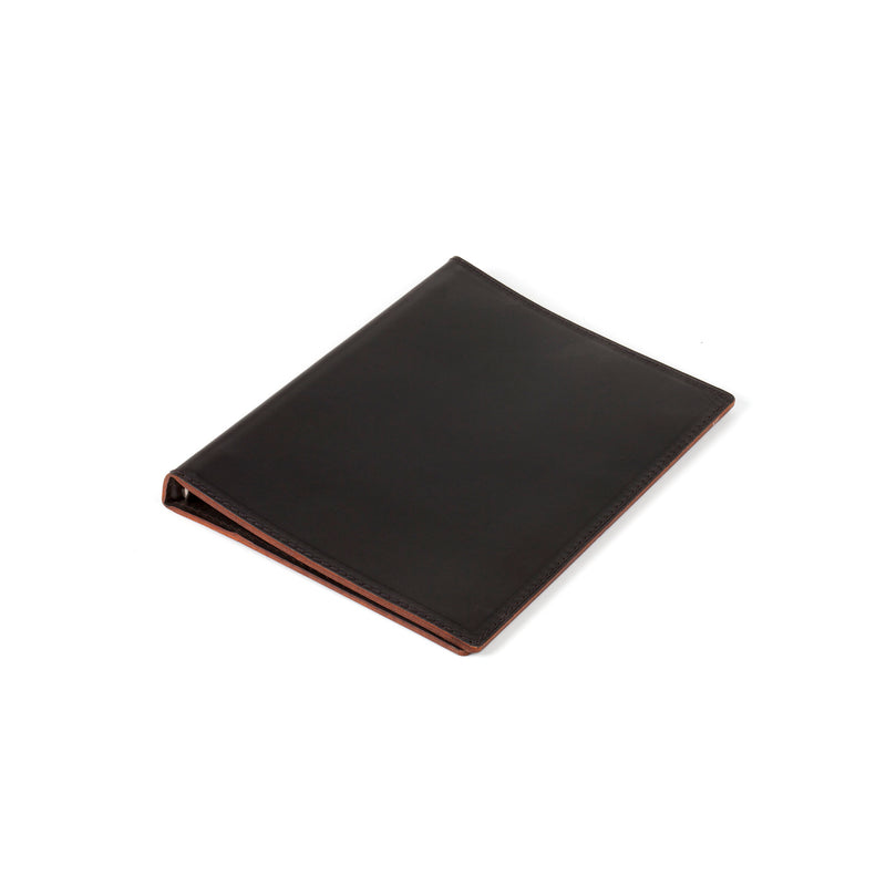 A slim, black leather Werkstätte Carl Auböck Telephone Register #5116/1 with a visible brown edge lies flat on a white background, exuding timeless elegance reminiscent of a classic Viennese townhouse design.