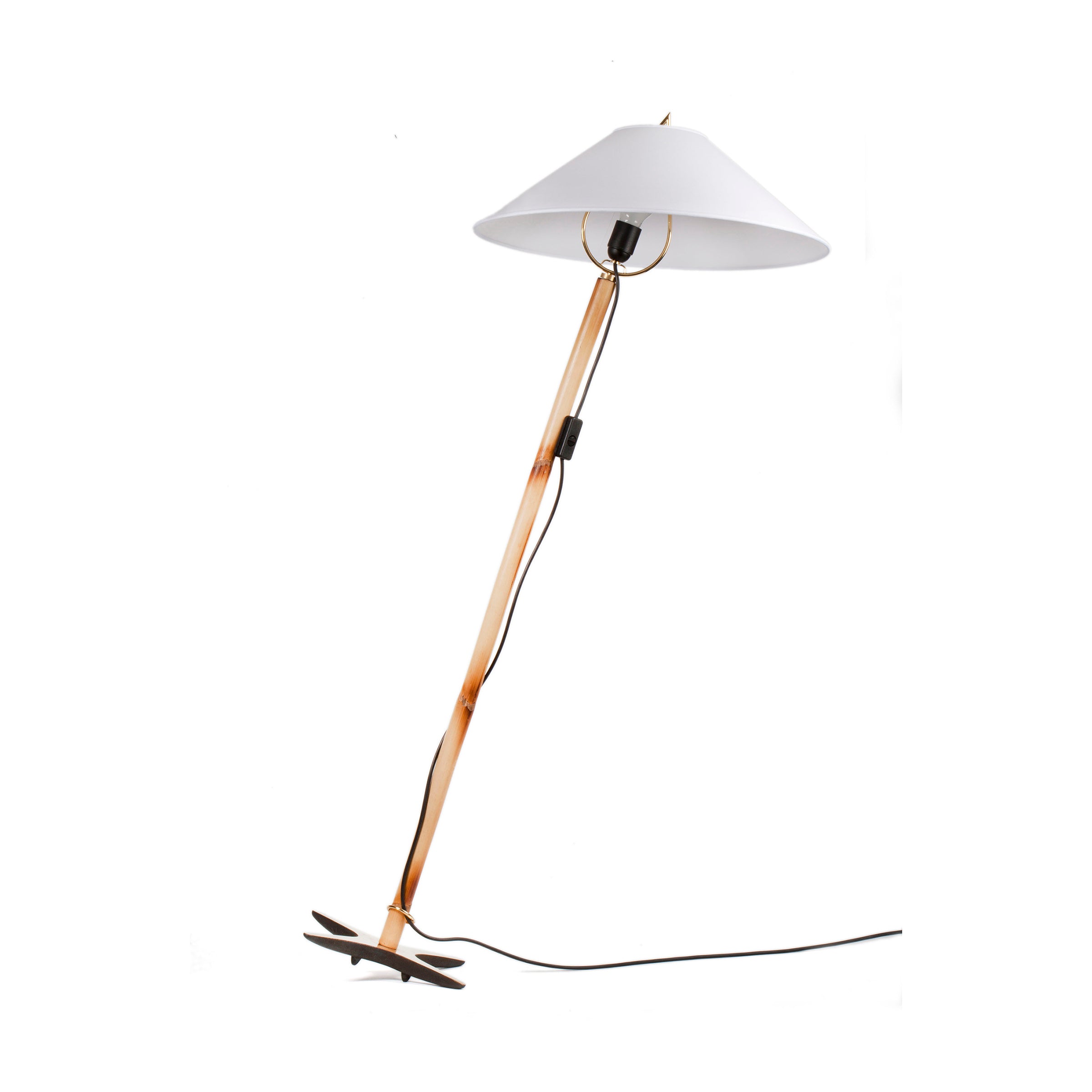 The Werkstätte Carl Auböck X-Lamp #3881 is a modern floor lamp with a wooden pole and white conical shade, reminiscent of Carl Auböcks designs. It features a unique cross-shaped base for its leaning structure and is complemented by a black power cord.