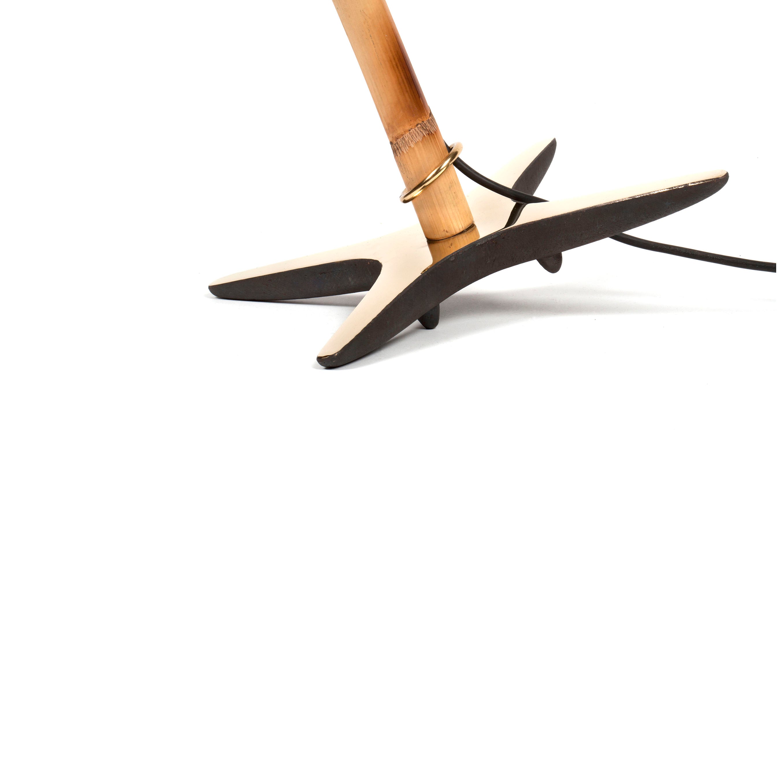 Close-up of the X-Lamp #3881 by Werkstätte Carl Auböck, showcasing a wooden stand with a triangular black base and a circular gold ring near the top. A black cable is elegantly coiled around it, set against a plain white background.