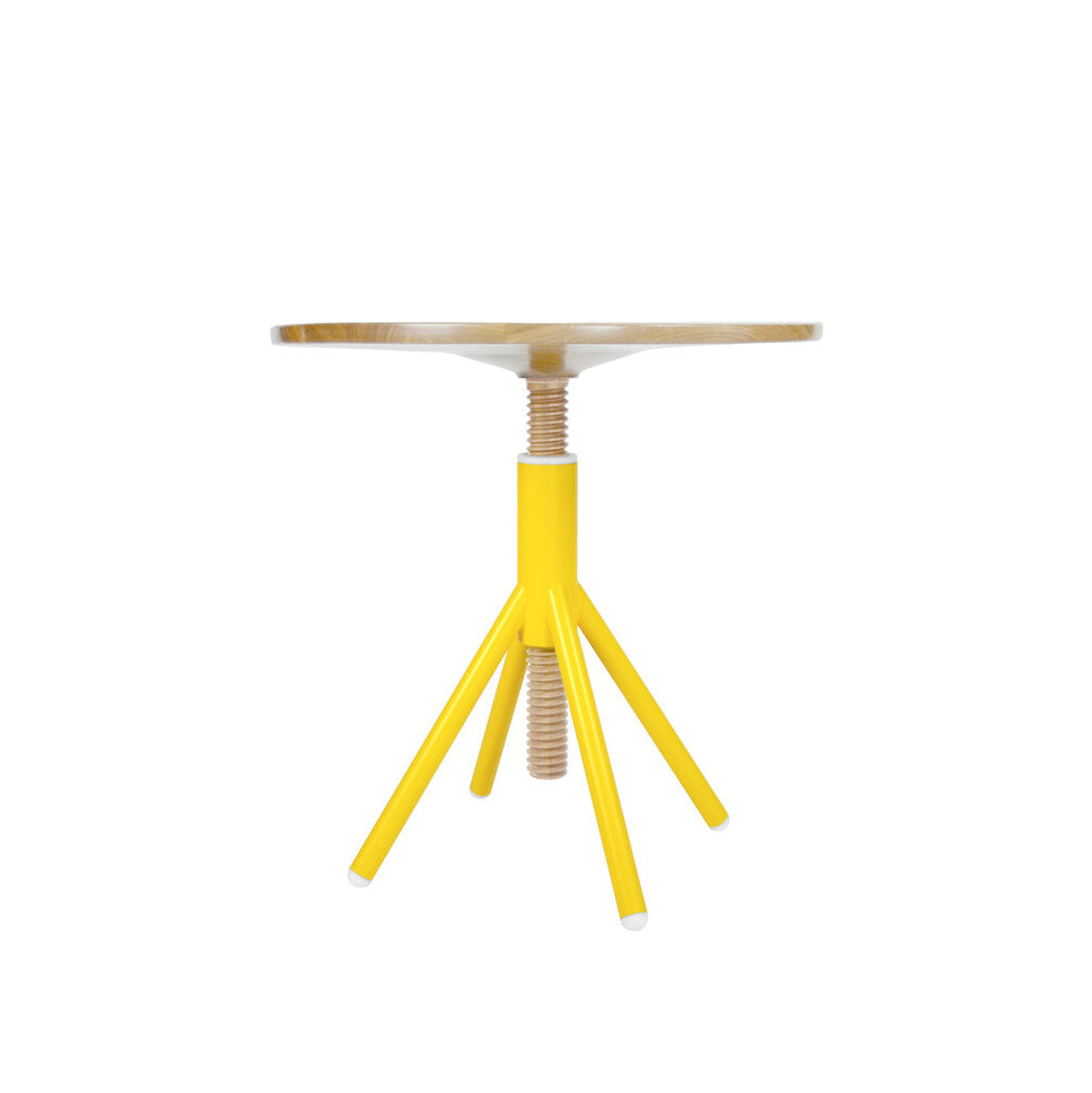 The Thread Family - Bistro Table by Coordination Berlin is a sleek side table with a round walnut wood top and a vibrant yellow, screw-inspired welded steel base featuring three angled legs.