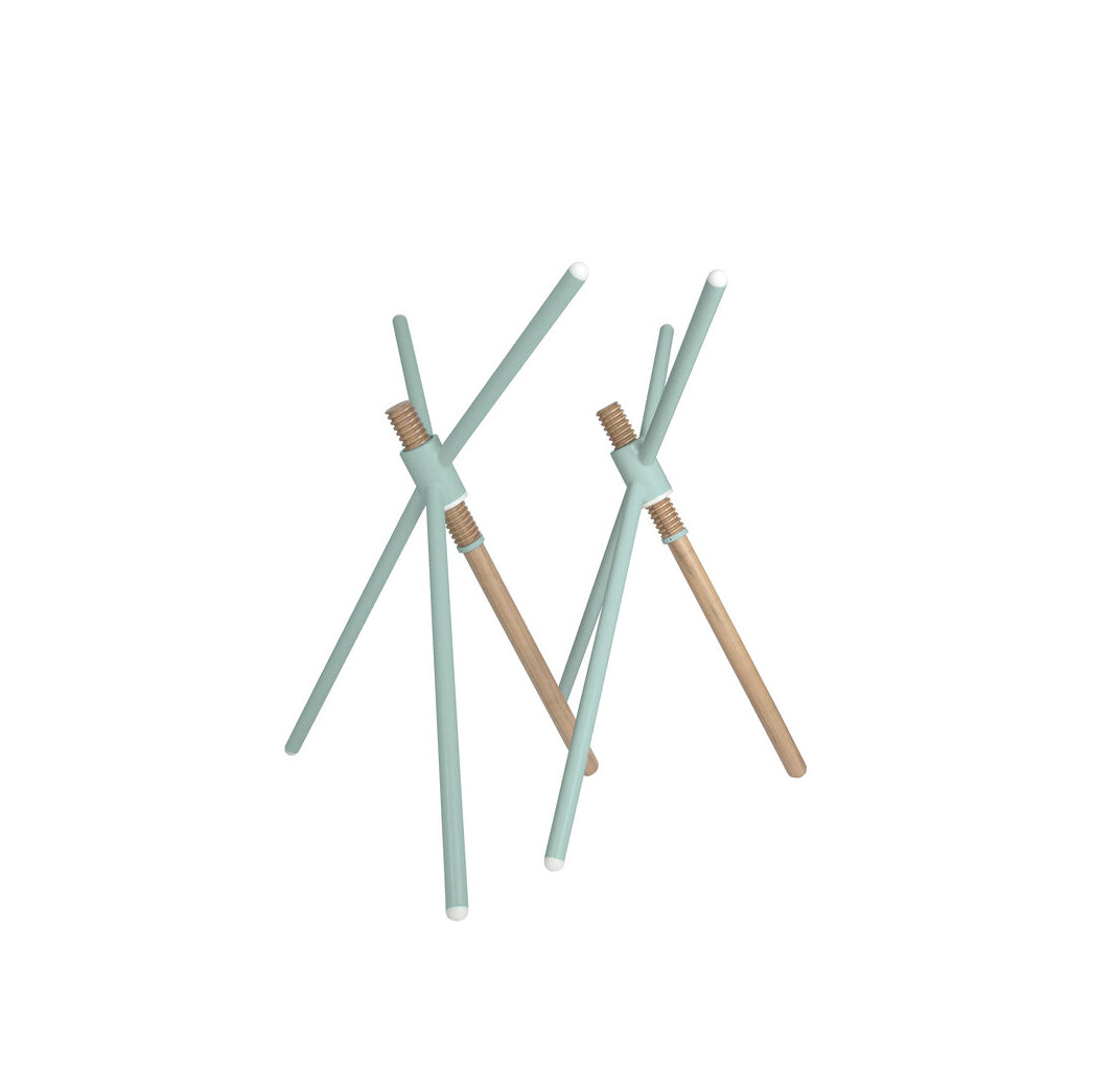 The Thread X sculpture by Coordination Berlin is a minimalist wooden piece with three intersecting light teal rods featuring white ends. Its contemporary, abstract design evokes avant-garde aesthetics, elegantly set against a plain white background.