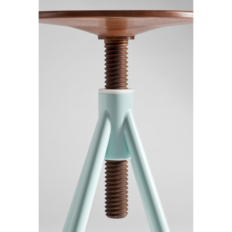 Close-up of the Thread Family - High Stool by Coordination Berlin, featuring a walnut wood seat and turquoise metal legs. The furniture piece includes a large central screw mechanism, seamlessly blending materials against a neutral background.