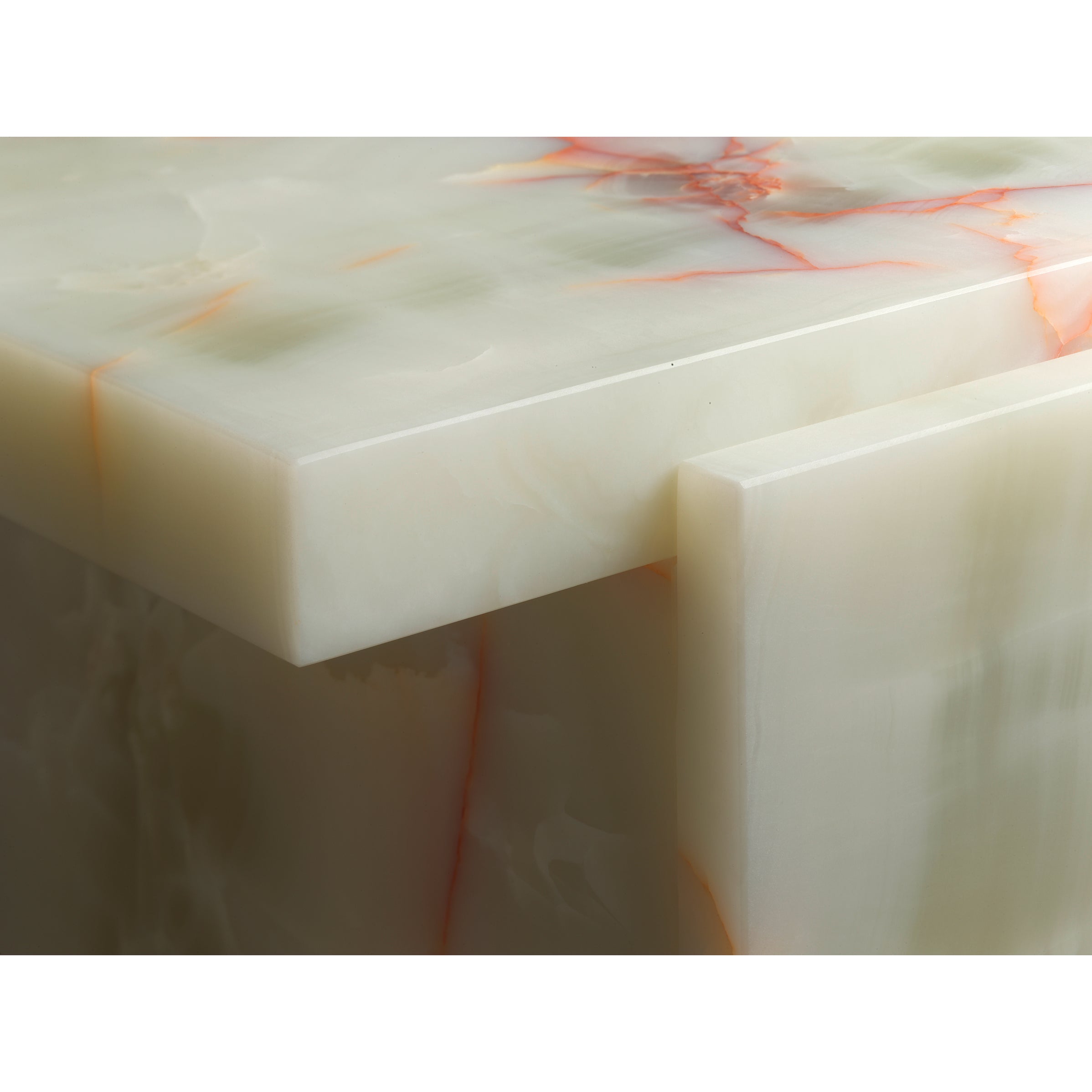 Close-up of the E15 DT02 TORE ONYX table, featuring a smooth pale green Art Deco onyx surface with subtle orange and red veining. The photo accentuates its corner and thick slab design, reminiscent of David Thulstrups sophisticated style.