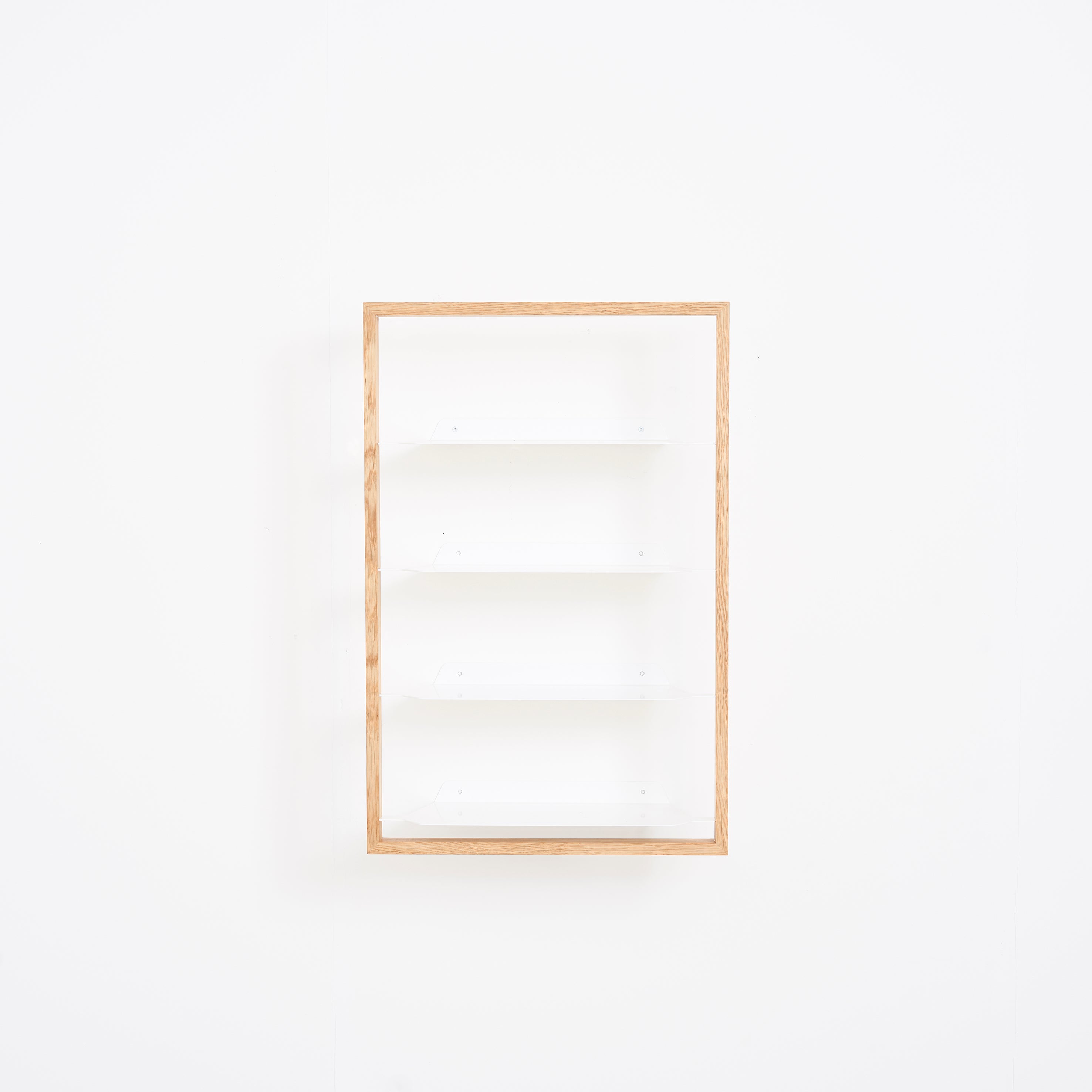 The Basti by Das kleine b is a minimalistic wall-mounted bookshelf with four powder-coated steel shelves and a rectangular oak frame, set against a plain white background.