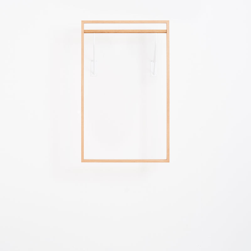 The Gardero-b by Das kleine b is a minimalist wooden square frame with two transparent brackets, designed to maximize wardrobe space on a white background. Its design is sleek and simplistic.