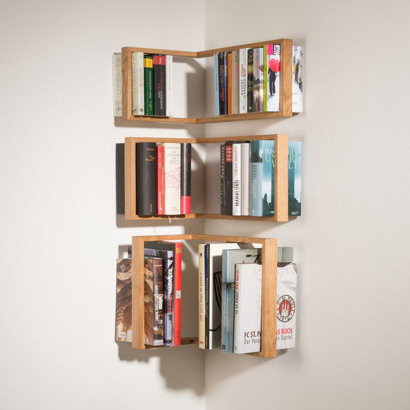 The b corner - Sale by Das kleine b is a solid wooden, minimalist floating wall-mounted corner bookshelf. It features three vertical tiers to showcase books, efficiently uses corner space, and enhances room aesthetics with its light wood design that blends style with functionality.
