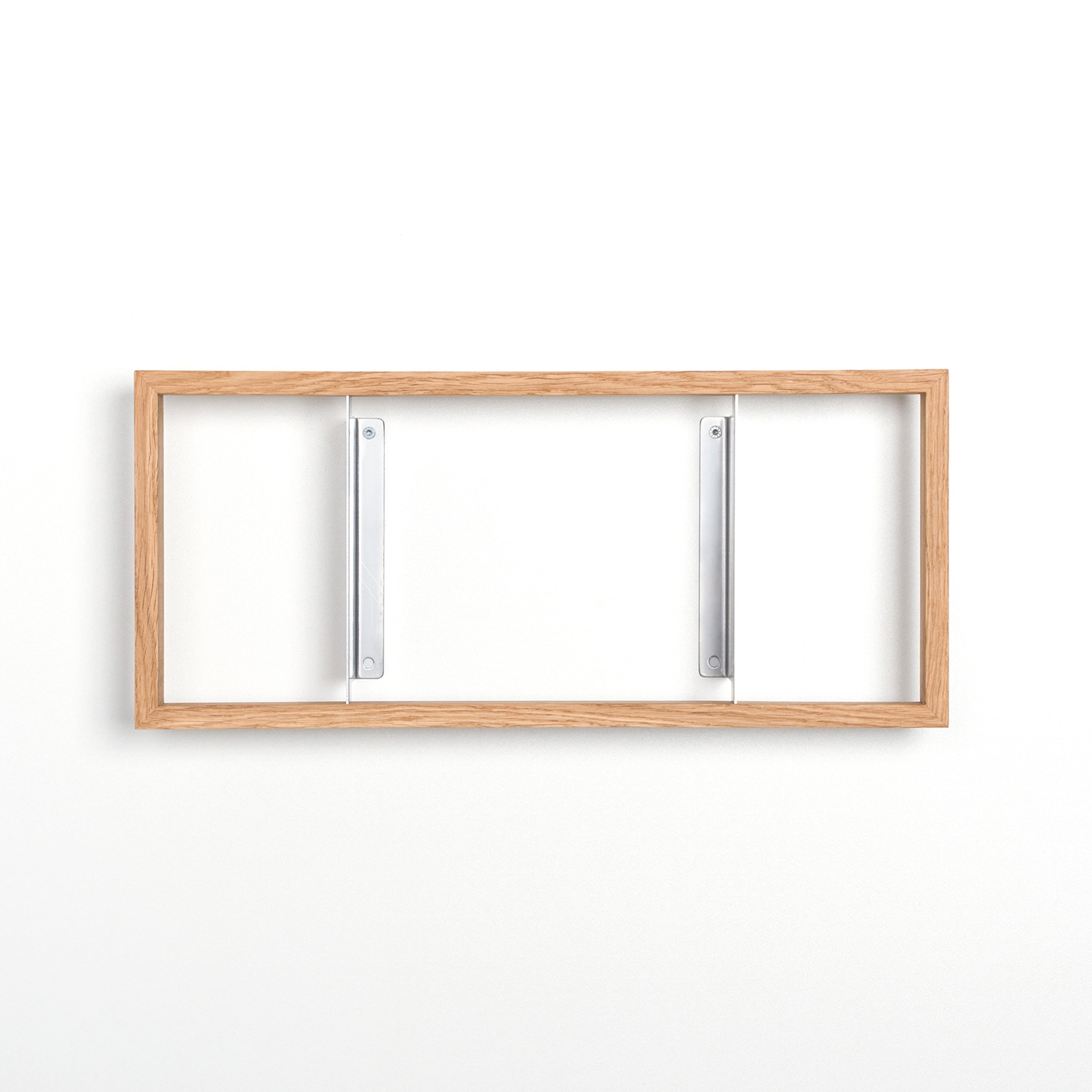 The b 7.6 by Das kleine b is a minimalist wooden rectangular frame featuring two vertical steel angles, mounted on a plain white wall, reminiscent of floating bookshelves.