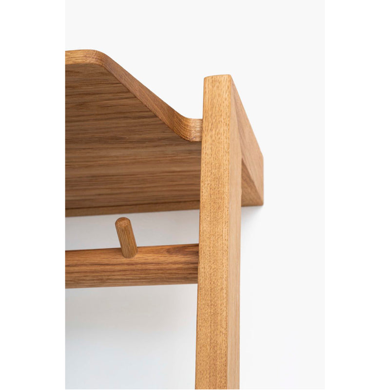 A close-up shows the Das kleine b Gardero-b with Hook Rail, featuring a minimalistic wooden shelf crafted from oiled oak. Its light brown finish, rounded peg, and corner junction are highlighted against a plain white background, perfect as corridor furniture.