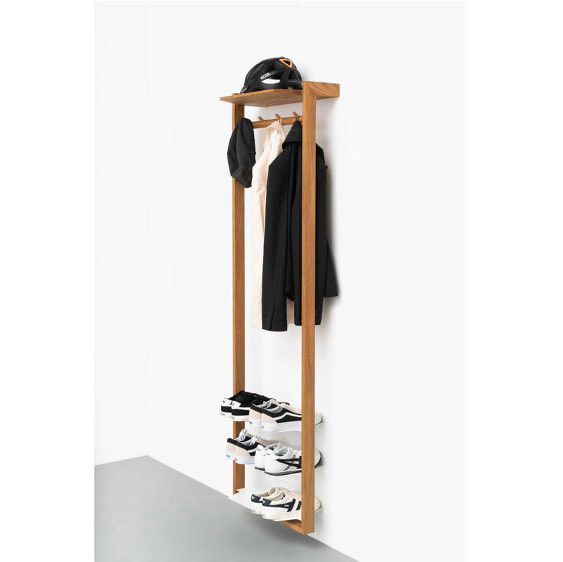 The Gardero-b by Das kleine b, a minimalist oiled oak wall-mounted coat rack, accommodates two jackets, a cap, and trousers. Below it are shelves holding six pairs of black and white shoes; ideal for corridors against a plain white wall.