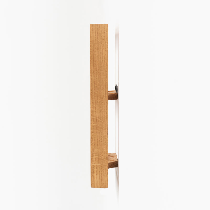 Side view of the Spice Rack Bocuse by Das kleine b, mounted on a wall, showcasing its oak construction and natural wood texture. The minimalistic design contrasts starkly against the white wall with its light brown frame.