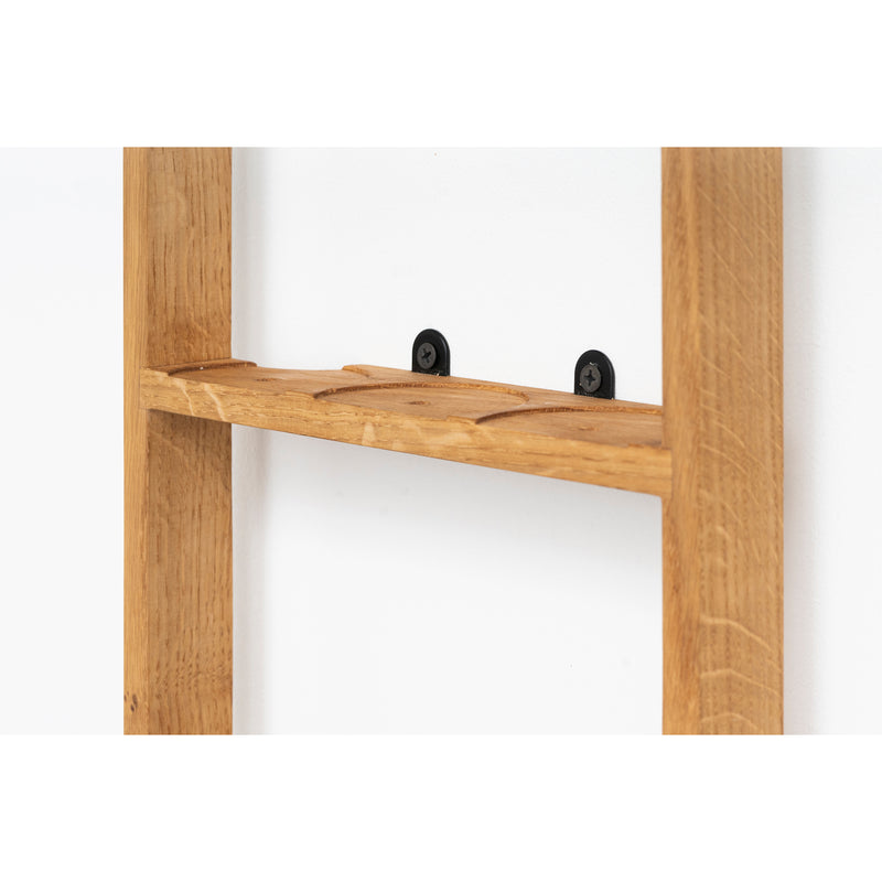 Close-up of the Das kleine b Spice Rack Bocuse, a polished oak shelf with two black hooks. This light brown shelf fits snugly between vertical wood panels, ideal for storing spice jars while beautifully contrasting the natural wooden texture.