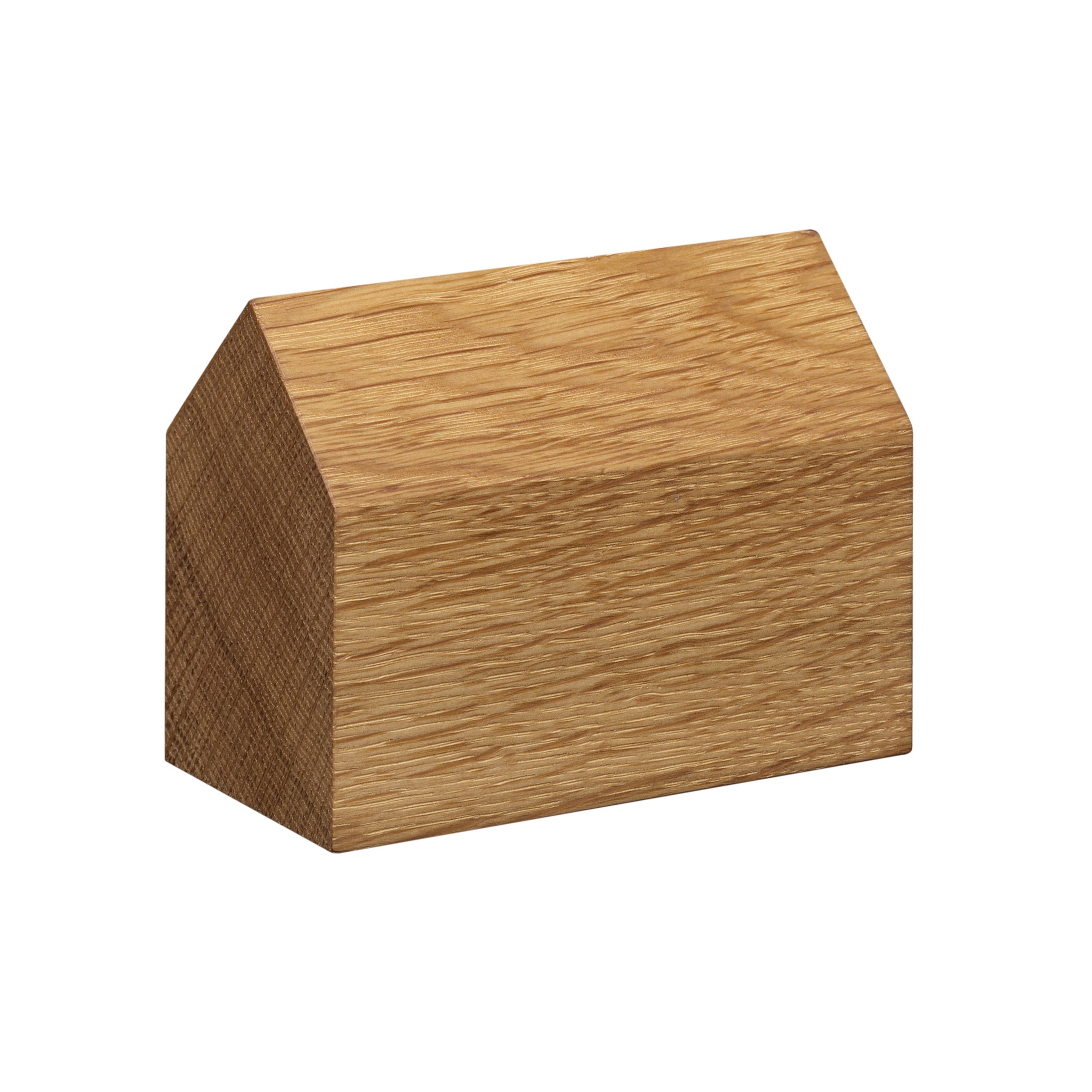 The AC10 HAUS paperweight by E15, crafted from European oak, resembles a house with its triangular roof and has visible wood grain for rustic charm. It rests elegantly against a plain white background.
