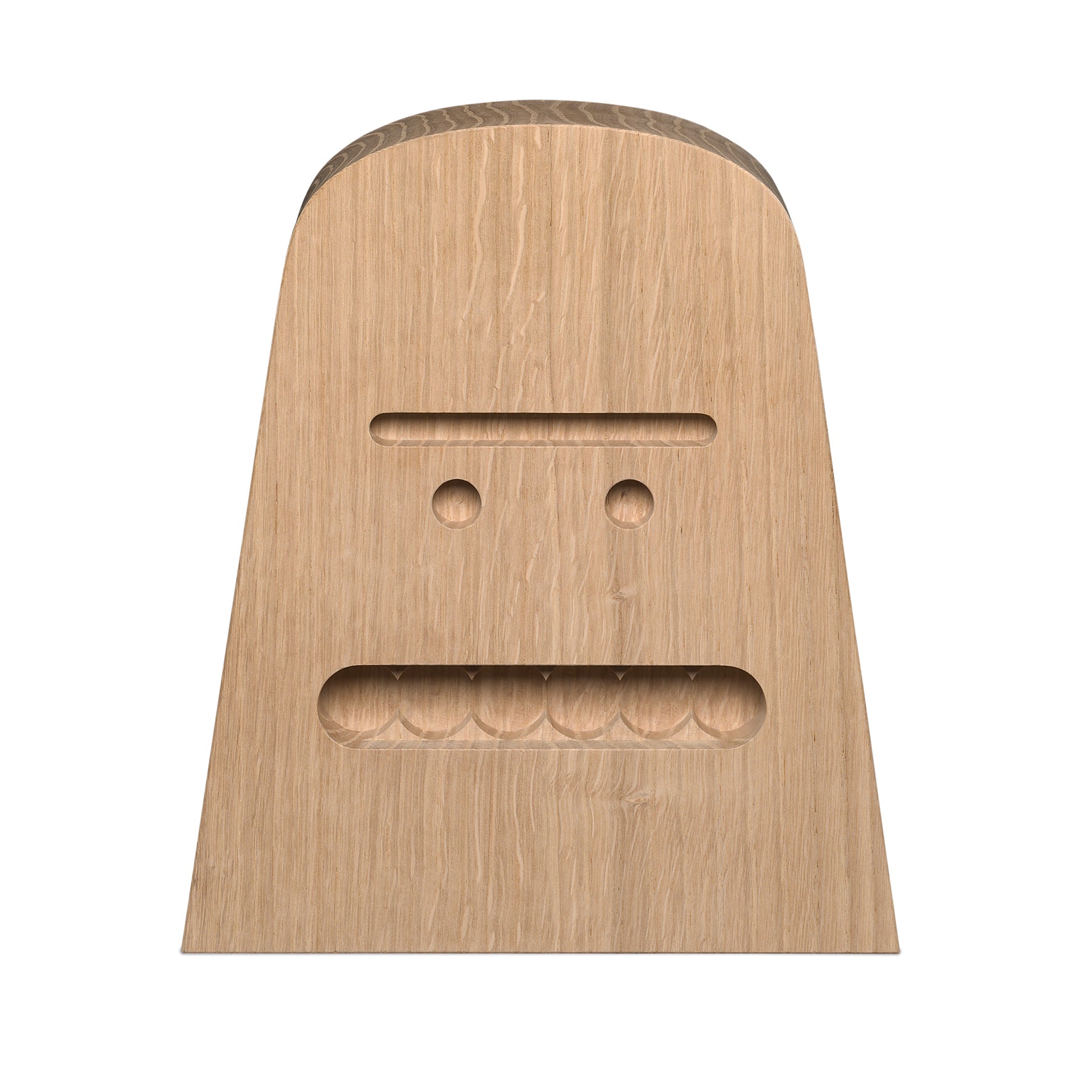 The AC17 BIG B solid wood block by E15 features carved geometric shapes creating a simple face with two circular eyes and a horizontal mouth slit. Its untreated oak texture highlights the natural grain patterns.
