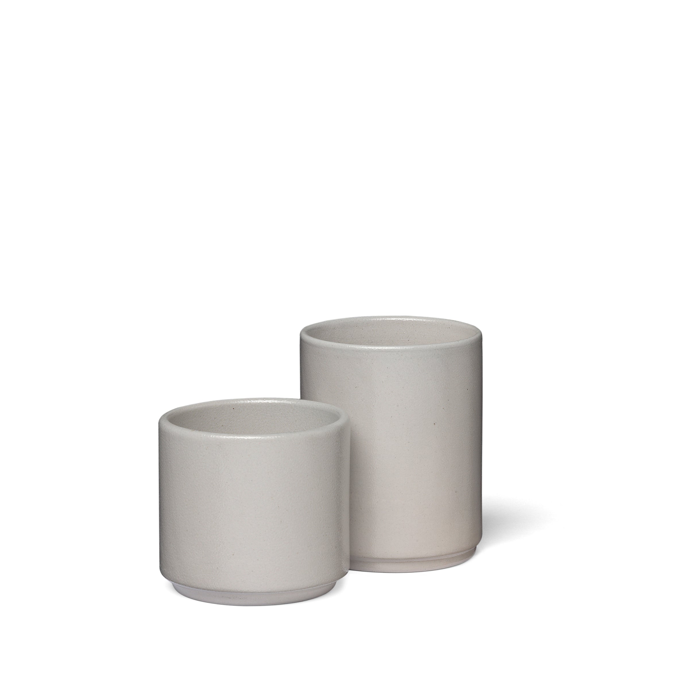 The AC19 SALINA by E15 features two minimalist ceramic planters with a smooth, matte finish in modern design. Displayed against a white backdrop, the planters are light gray stoneware; the left one being smaller adds to their aesthetic appeal.