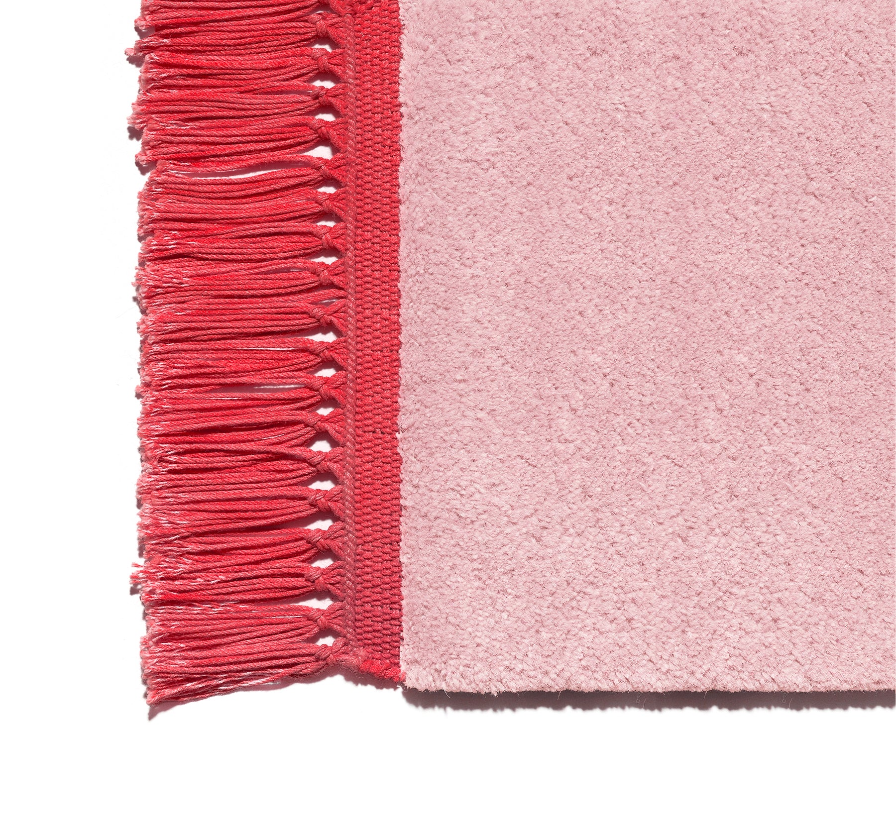 Close-up of CP03 KAVIR by E15, showcasing a pink textured fabric reminiscent of modern carpet design, featuring a red fringed border with evenly spaced looped threads on the left side for decorative appeal.
