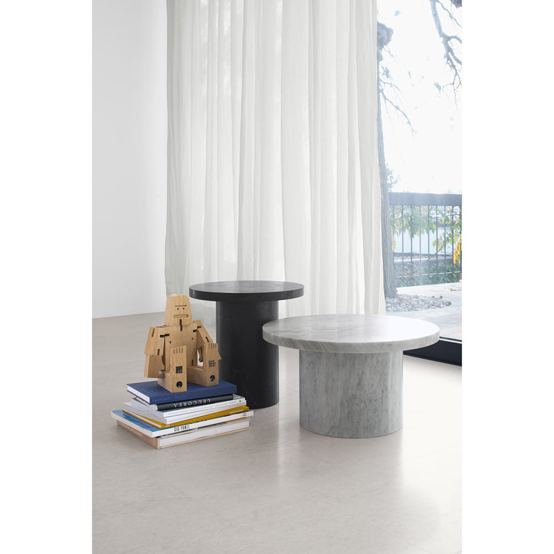 Near airy curtains and a bright window, the black and gray ENOKI MIGOTO side tables by E15 stand elegantly. A stack of books and a wooden robot toy lie next to them on the floor, with sunlight capturing an artful balance curated by E15 design.