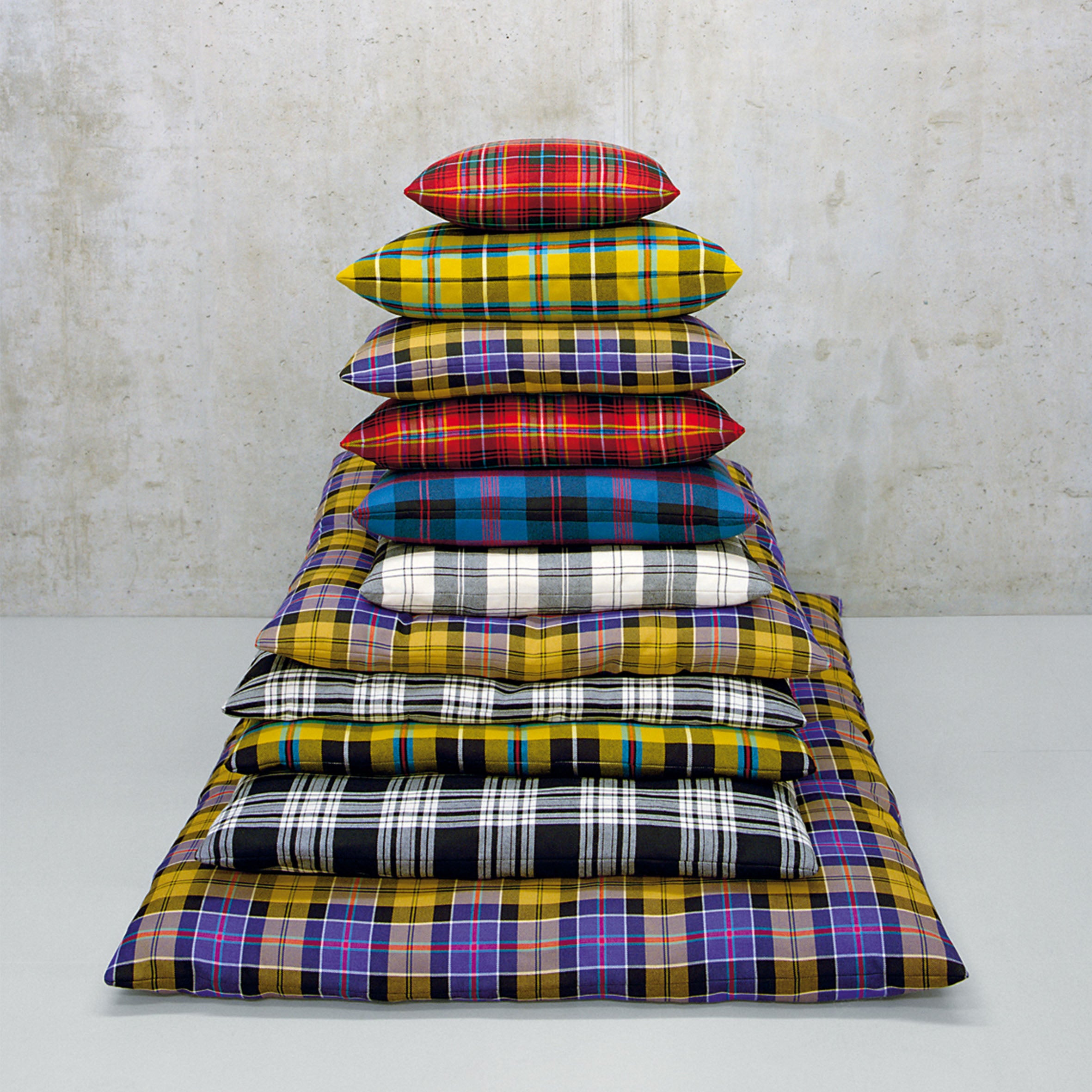 The CU06 NIMA collection by E15 adds charm with colorful tartan-patterned cushions and blankets in yellow, red, blue, and black. Their minimalist gray background makes these accessory cushions perfect for any cozy space.