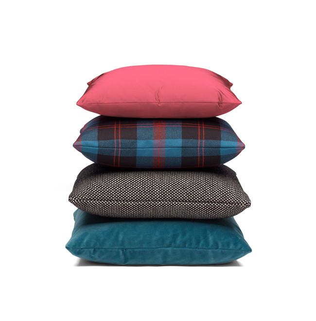 A stack of four E15 accessories from the CU06 NIMA collection against a white background. From top to bottom: solid pink, blue plaid with red and black, black with white polka dots, and solid teal. Perfect for adding color and texture to any space.