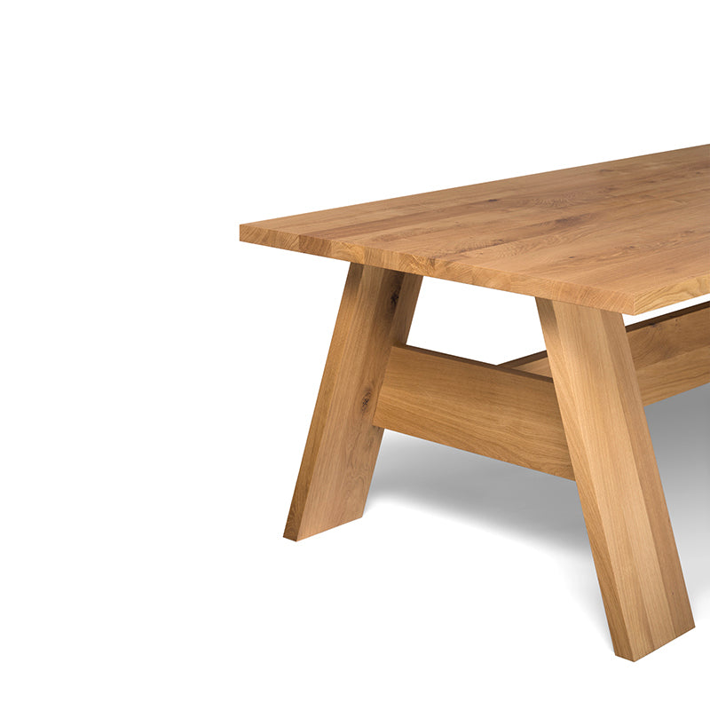 The DC01 FAYLAND table by E15 showcases a minimalist design with polished solid wood, a flat top, and sturdy A-shaped legs extending left. The natural wood grain patterns embody the elegance reminiscent of David Chipperfields style.