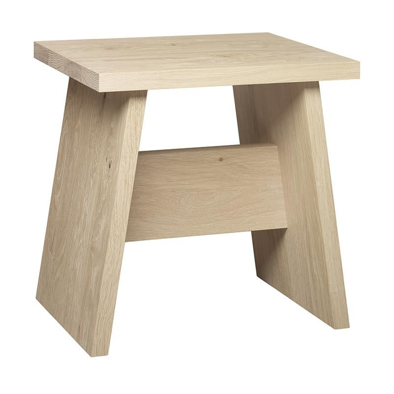 The DC03 LANGLEY by E15 is a compact, lightweight side table made of solid European walnut. It boasts an angular modern design with a rectangular top, two slanted side supports, and a flat brace that connects the sides. Its smooth finish beautifully highlights the woods natural grain.