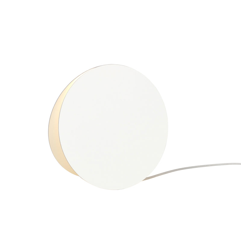The LT05 NORTH Floor Light by E15 is a minimalist, round white lamp with a thin, concealed base that emits soft, atmospheric light. Its power cord extends from the back and rests on a plain white surface, exuding abstract geometry. Now available on sale!.