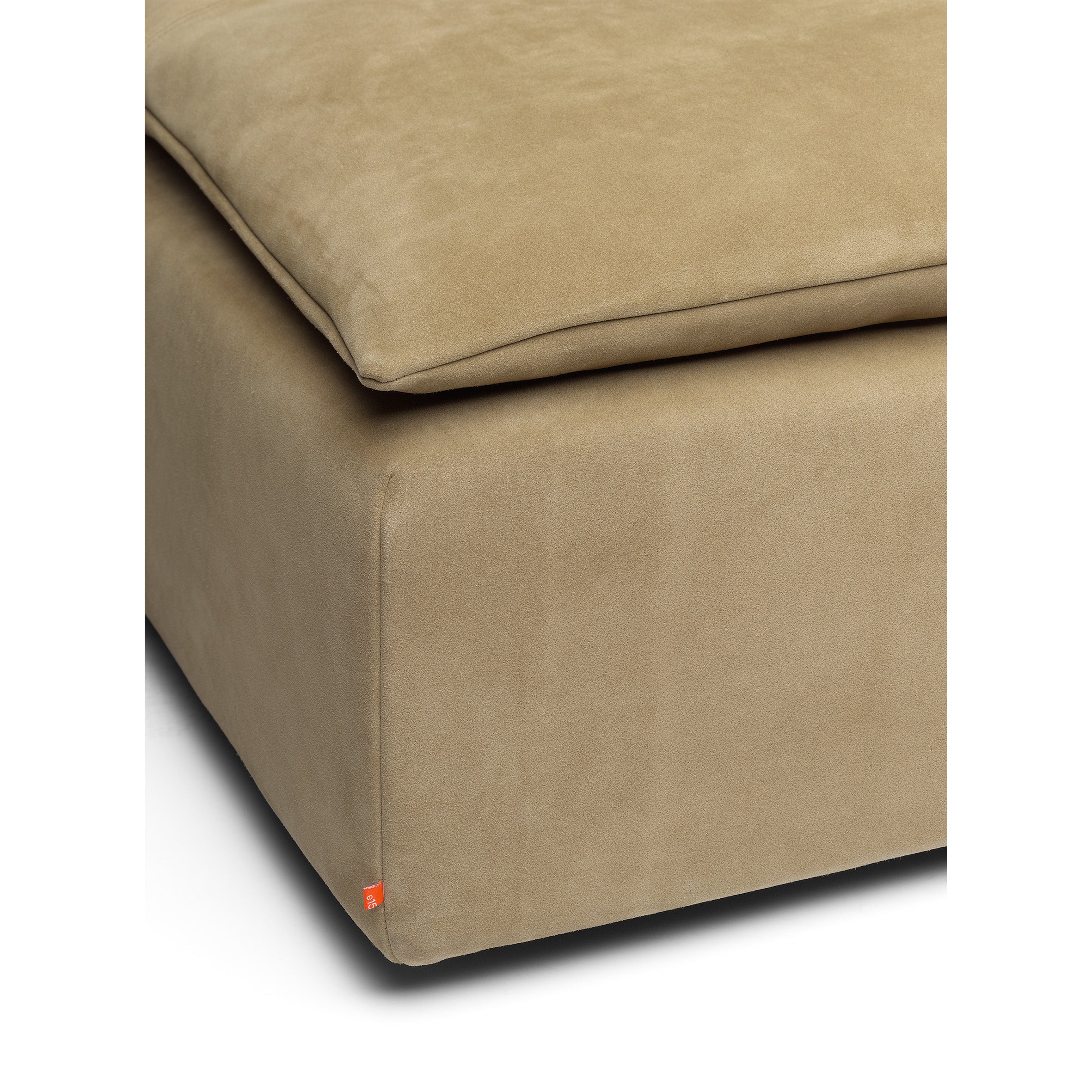 The E15 SF03 SHIRAZ ottoman features a plush beige suede cushion with clean lines and modern design, highlighted by an orange corner tag.