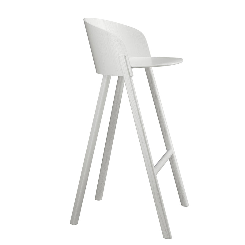 The ST12 OTHER by E15 is a modern, minimalist tall stool with a light gray finish. Part of a sleek series, it features a curved backrest and round seat for enhanced comfort, supported by four angled legs connected by a horizontal footrest.