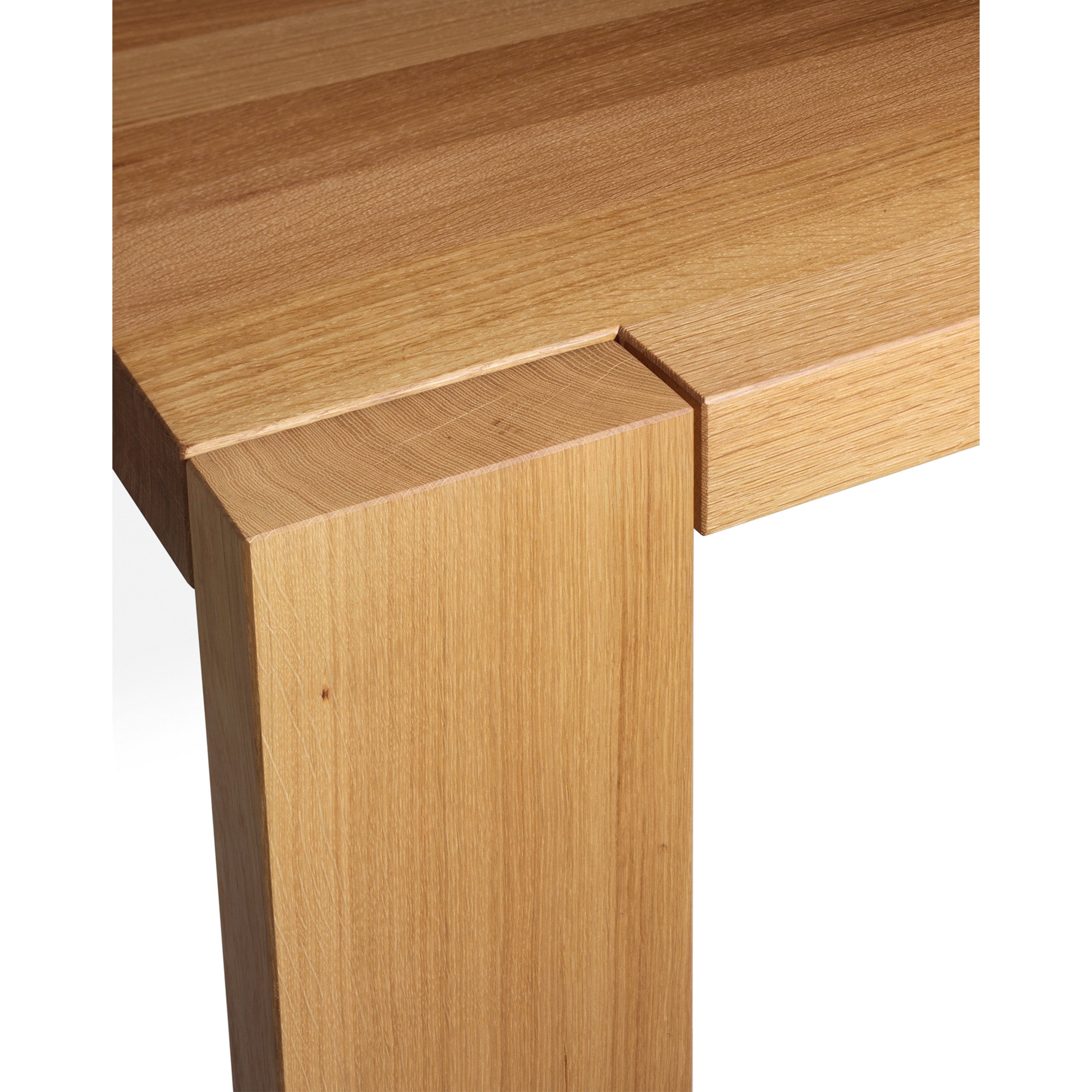 A close-up of the TA17 LONDON table corner by E15 shows a seamless design with a smooth alignment of the solid wood leg and tabletop. The visible wood grain enhances its natural texture and warm tone, highlighting the elegance of this piece.