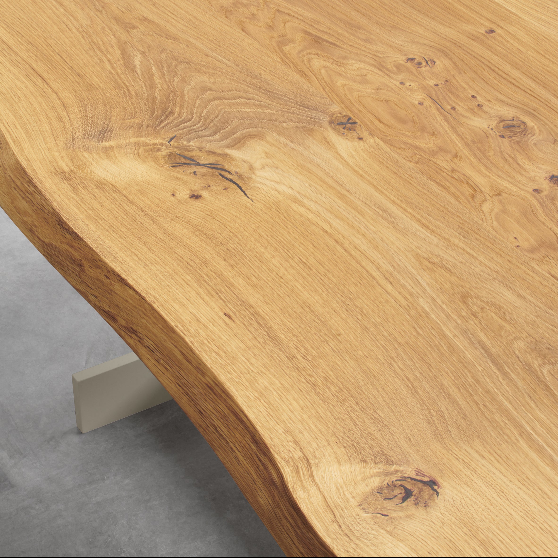 Close-up of the TA23 KAZIMIR RAW table by E15, crafted from European oak with a natural wavy edge. The light brown finish highlights the wood grain and knots, resting on a geometric base atop a smooth gray floor.