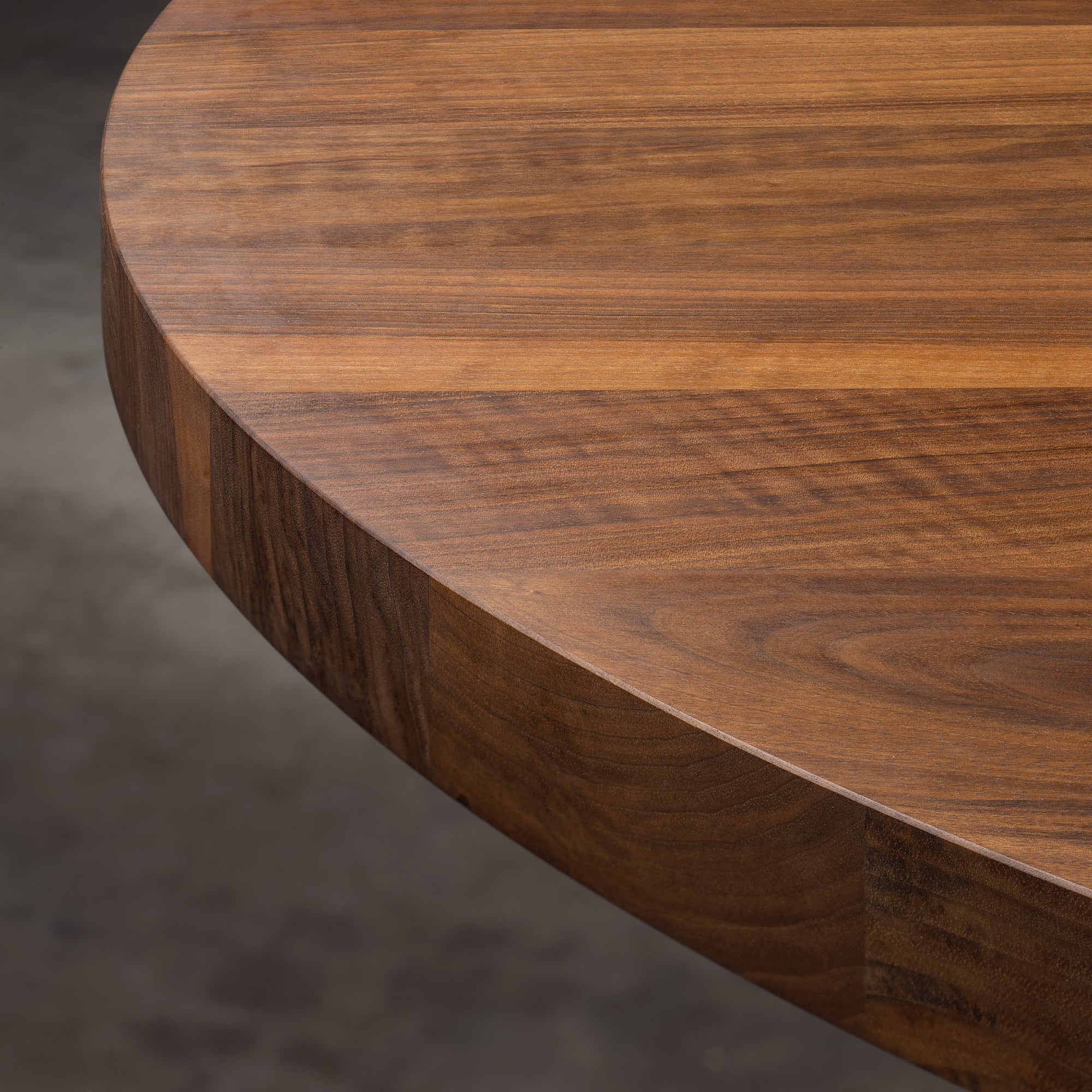 Close-up image of the TA24 ASHIDA Oval table by E15, crafted from solid wood with a polished surface. The rich European walnut grain is prominently visible, showcasing natural patterns and textures, with a softly blurred background highlighting its craftsmanship.