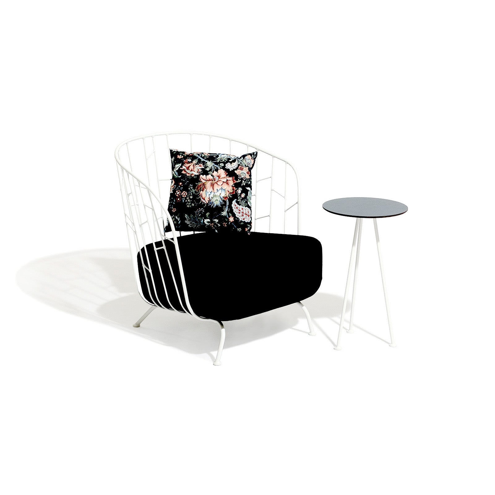A sleek white metal chair made from powder-coated steel with a black cushion sits by the Maj Lounge Table by Egoe. A pillow featuring a vibrant floral design enhances the chairs backrest, all set against a plain white background, ideal for highlighting chic outdoor furniture.