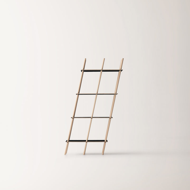The Es by Moormann, a minimalist wooden ladder, leans against a plain white backdrop. It features five rungs connected by thin black rods, showcasing sleek modern craftsmanship.