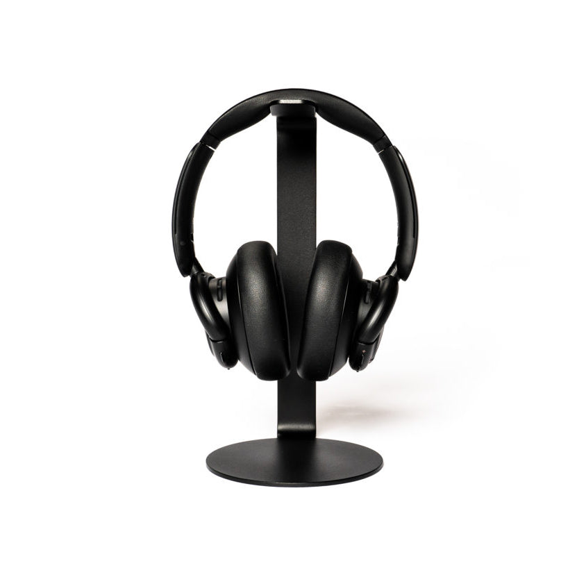 A pair of black over-ear headphones sits elegantly on the sleek, modern STÄNDER by Echtstahl, a minimalist headphone stand crafted from powder-coated steel, all set against a plain white backdrop.