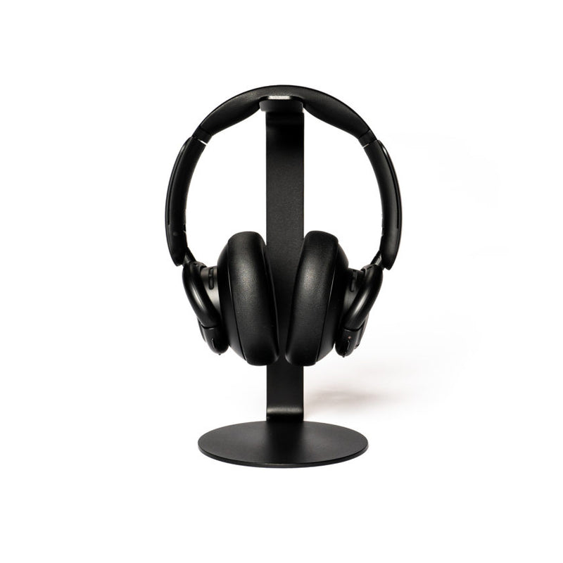 A pair of black over-ear headphones sits elegantly on the sleek, modern STÄNDER by Echtstahl, a minimalist headphone stand crafted from powder-coated steel, all set against a plain white backdrop.