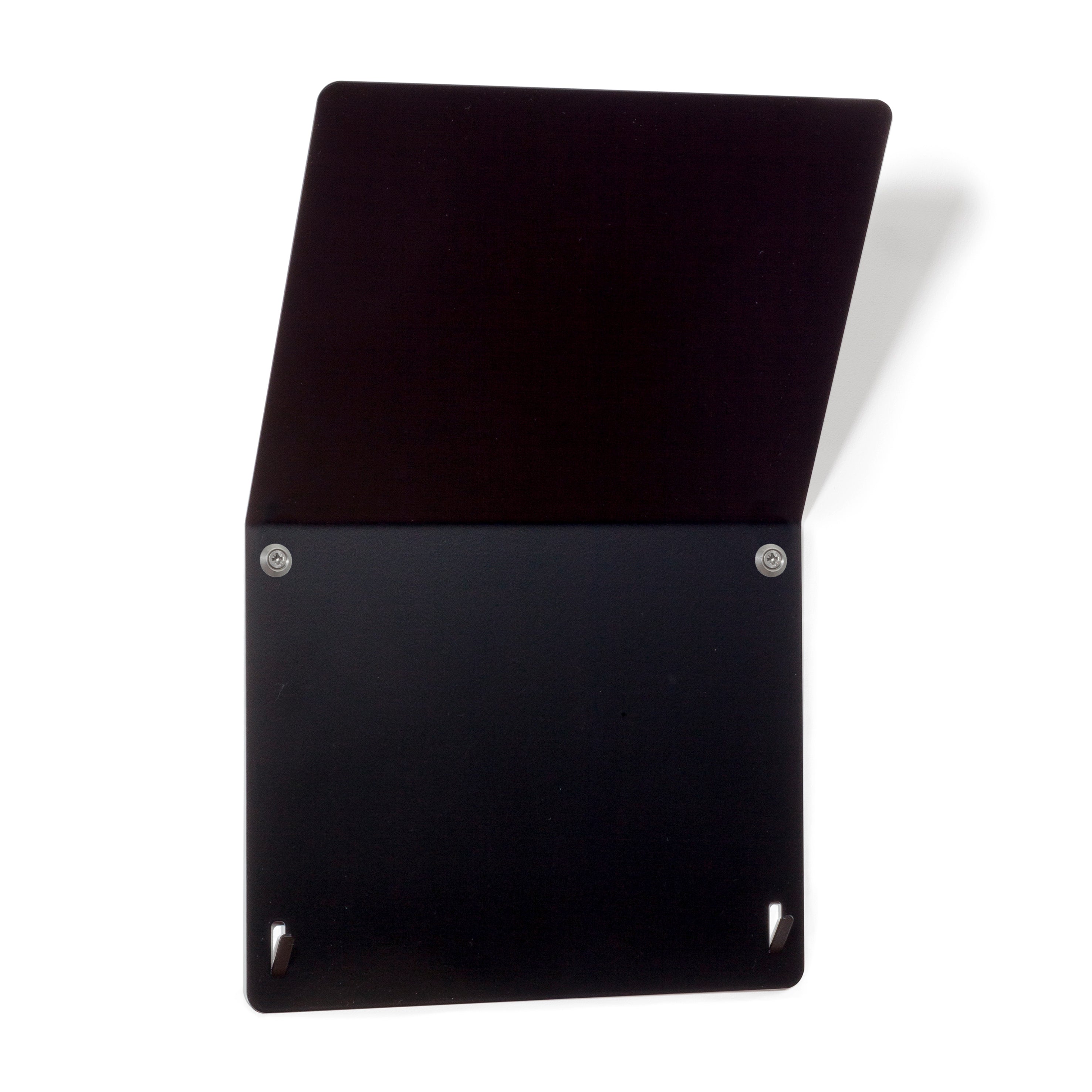 The Trik by Echtstahl is a black, wall-mounted organizer with a minimalist design, ideal for magazine storage. Featuring an upper flap thats slightly open, its crafted from smooth stainless steel with two visible screws and triangular cutouts at the bottom corners, set against a white background.