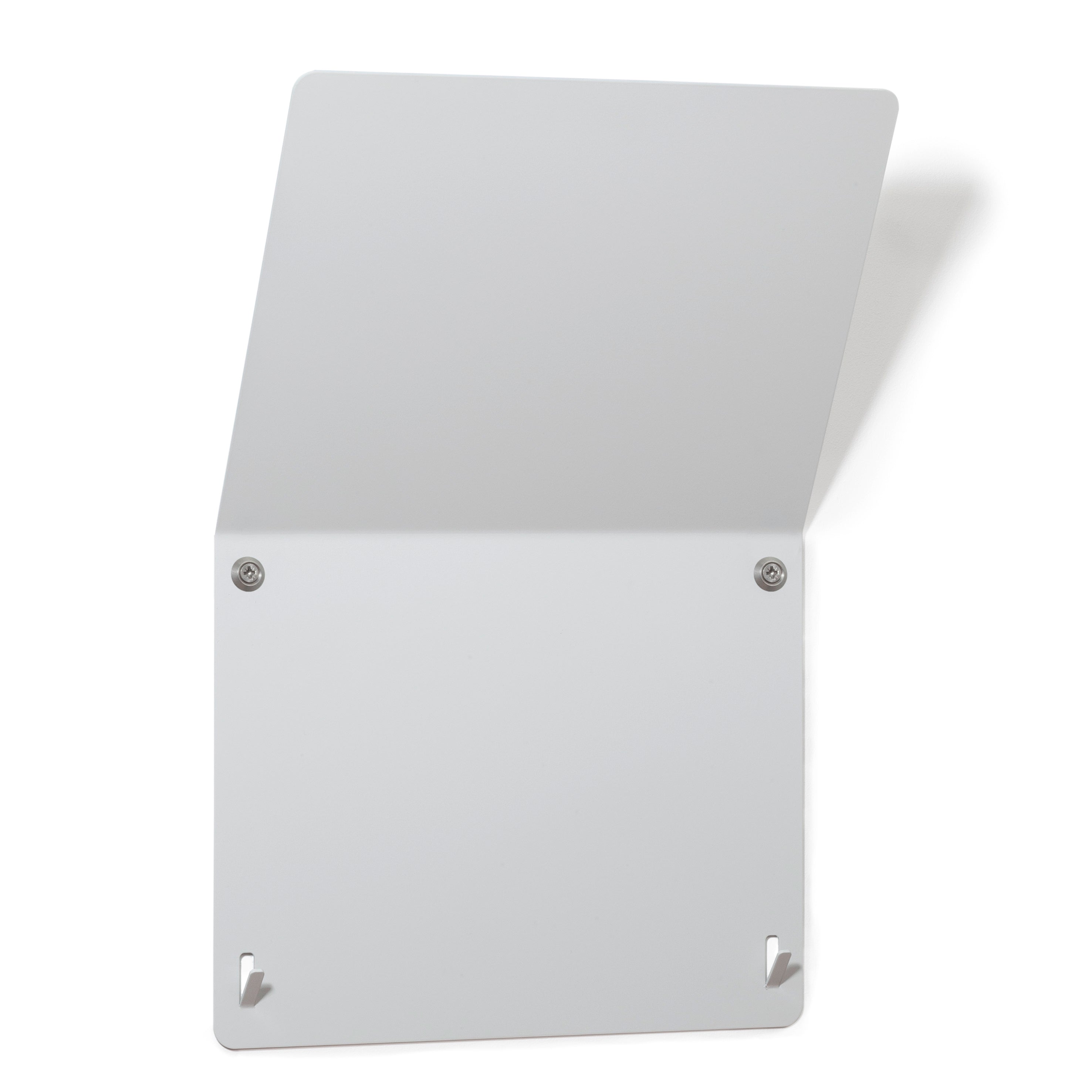 The Trik by Echtstahl is a minimalist wall-mounted stainless steel accessory with a simple rectangular design, featuring two top screws and two bottom slots. Angled slightly forward as a modular newspaper rack, it casts a soft shadow on its plain background.