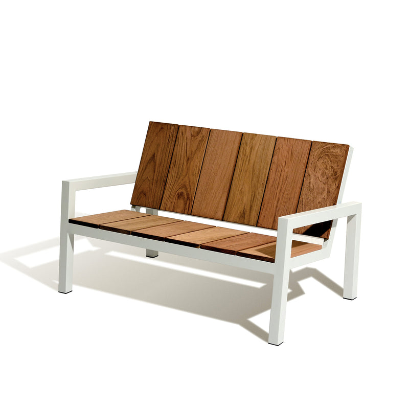 The Laurede Bench by Egoe features wide tropical wood slats on a wooden seat and backrest, complemented by straight metal legs and armrests against a plain white background, showcasing its modern minimalist design ideal for outdoor furniture enthusiasts.