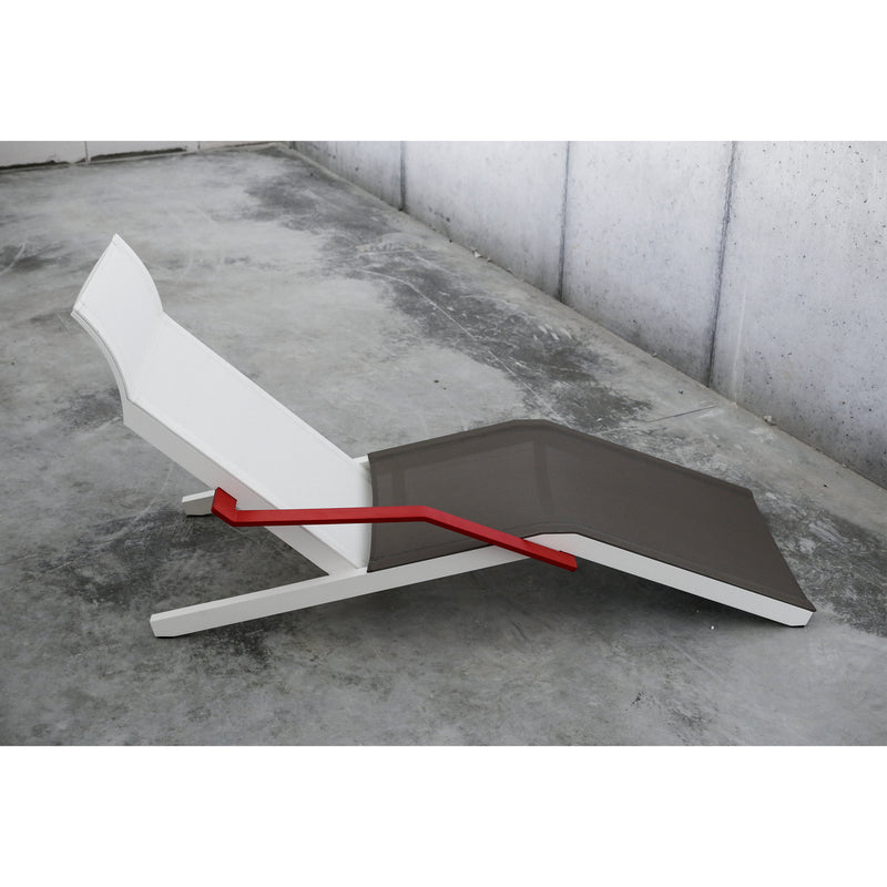 The Alva Deck Chair by Egoe boasts a modern design with a lightweight white frame, gray recliner, and vivid red side handle, perfect for a minimalist setting on a concrete floor.